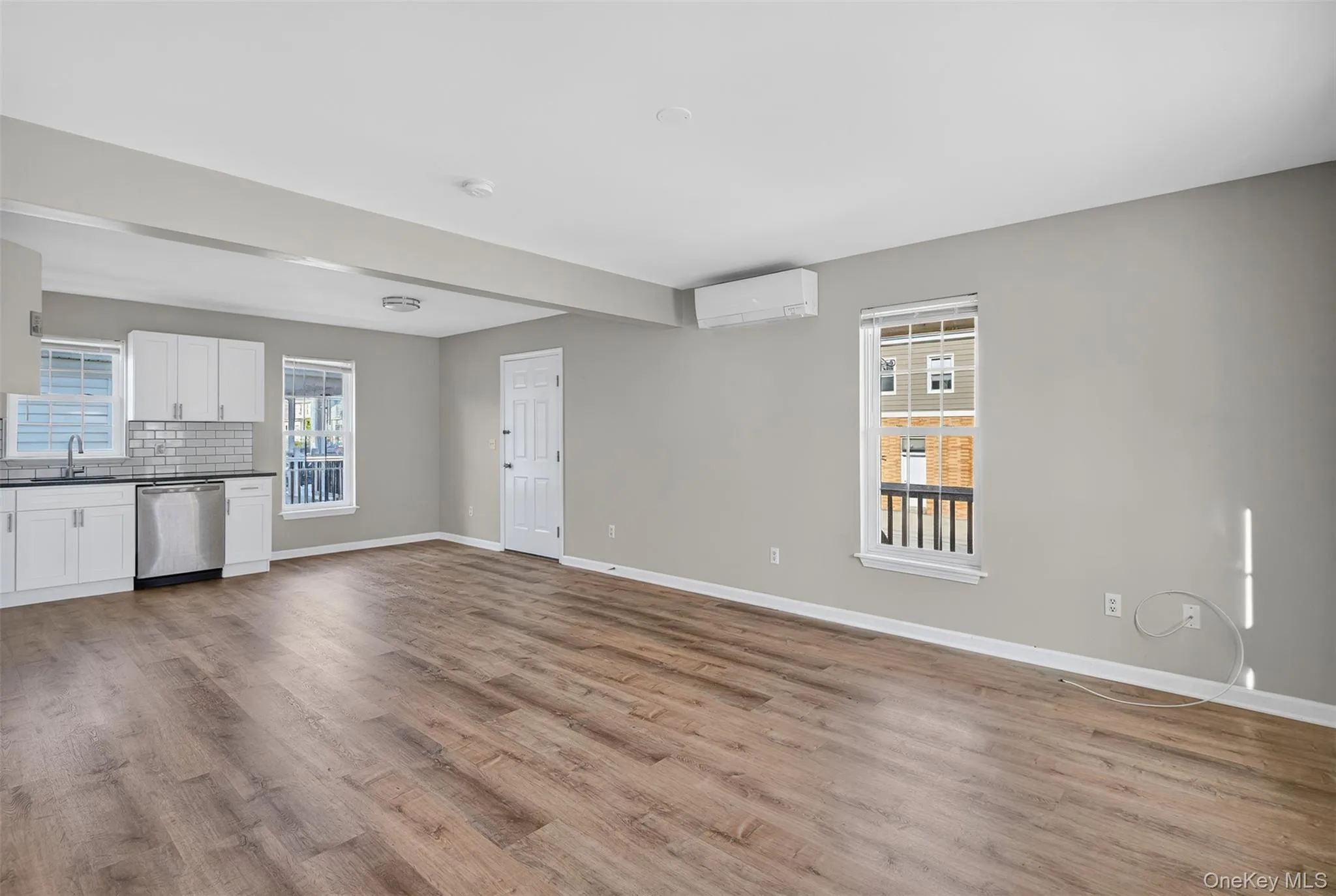 Unfurnished living room featuring light wood-type flooring and a wall mounted AC Unfurnished living room featuring light wood-type flooring and a wall mounted AC