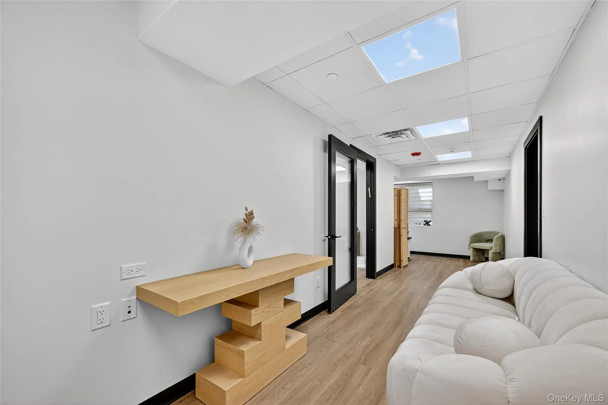 Corridor featuring a paneled ceiling and light wood-style floors Corridor featuring a paneled ceiling and light wood-style floors