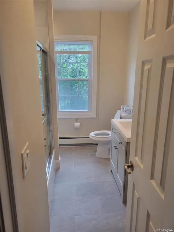 Bathroom with vanity, a baseboard heating unit, and light tile patterned floors Bathroom with vanity, a baseboard heating unit, and light tile patterned floors