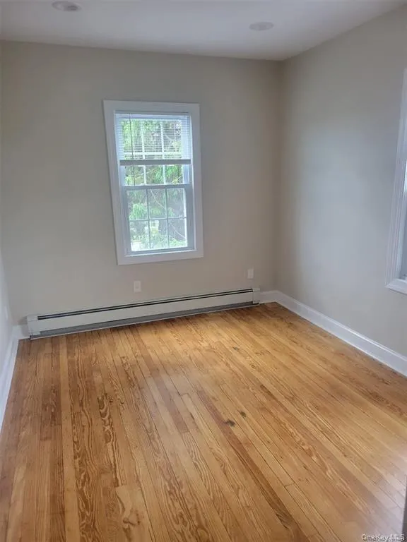 Unfurnished room with light wood-style flooring and baseboard heating Unfurnished room with light wood-style flooring and baseboard heating