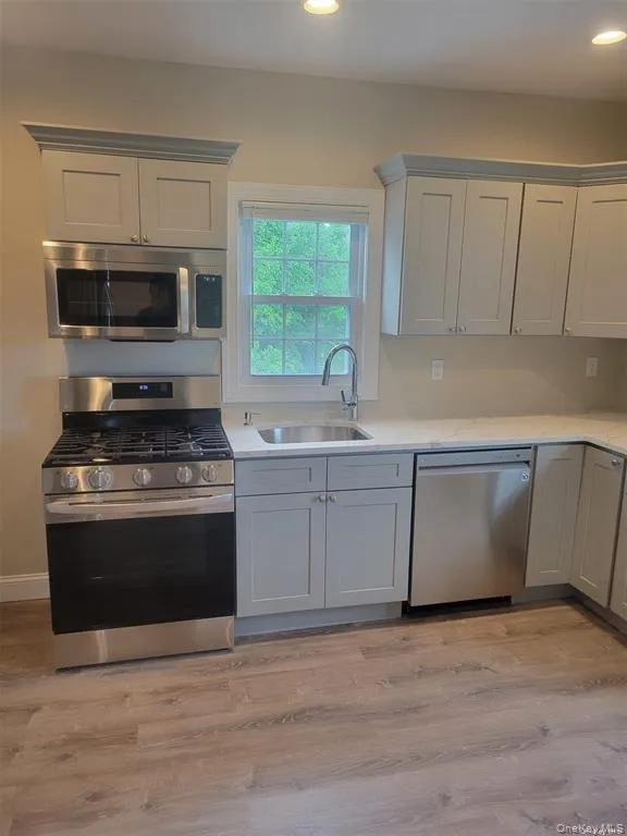 Kitchen featuring stainless steel appliances, light wood finished floors, light stone counters, and recessed lighting Kitchen featuring stainless steel appliances, light wood finished floors, light stone counters, and recessed lighting