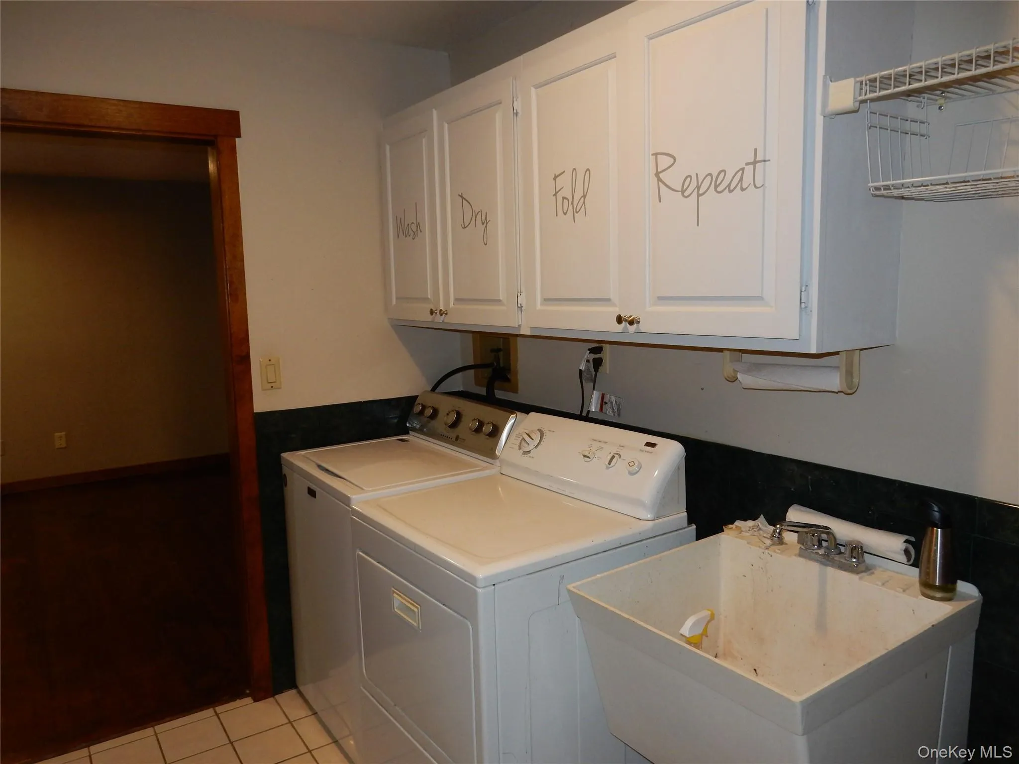 Washroom featuring light tile patterned floors, independent washer and dryer, and cabinet space Washroom featuring light tile patterned floors, independent washer and dryer, and cabinet space