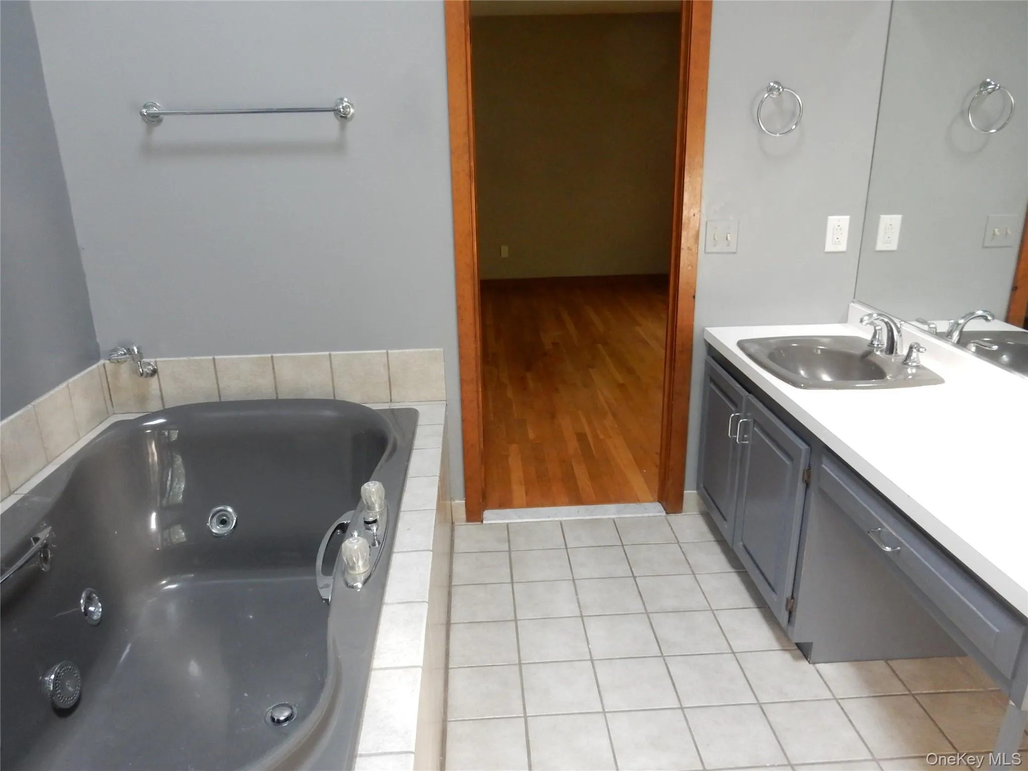 Bathroom featuring vanity, a tub with jets, and light tile patterned floors Bathroom featuring vanity, a tub with jets, and light tile patterned floors