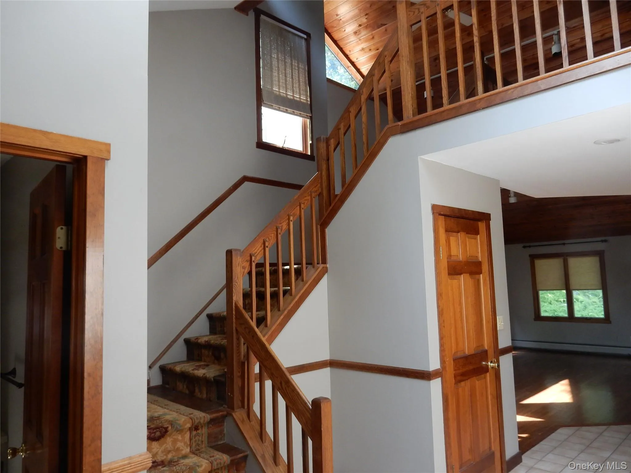 Stairway with healthy amount of natural light, a baseboard radiator, and high vaulted ceiling Stairway with healthy amount of natural light, a baseboard radiator, and high vaulted ceiling