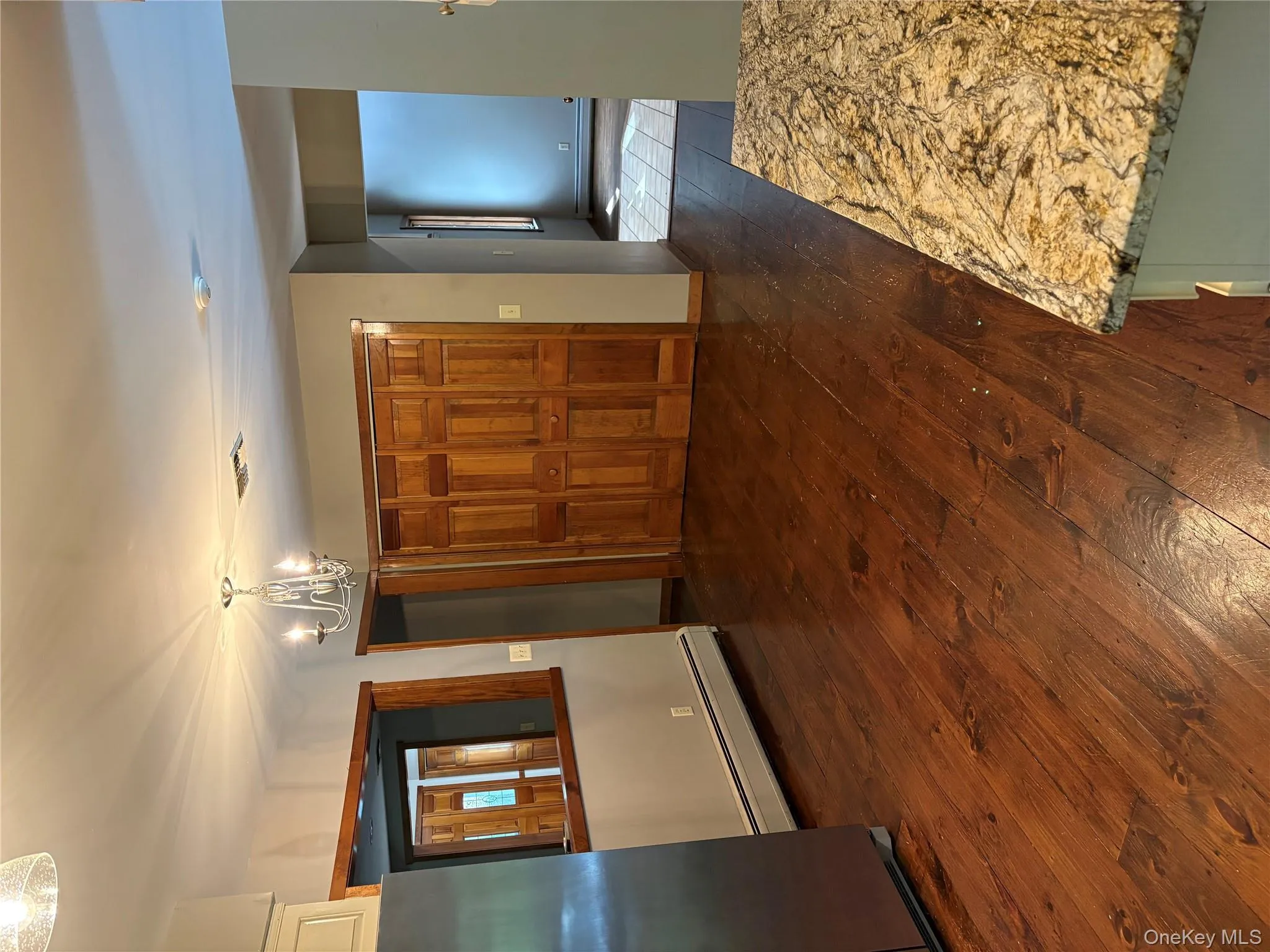 Unfurnished dining area with dark wood-style flooring, a baseboard radiator, and a chandelier Unfurnished dining area with dark wood-style flooring, a baseboard radiator, and a chandelier