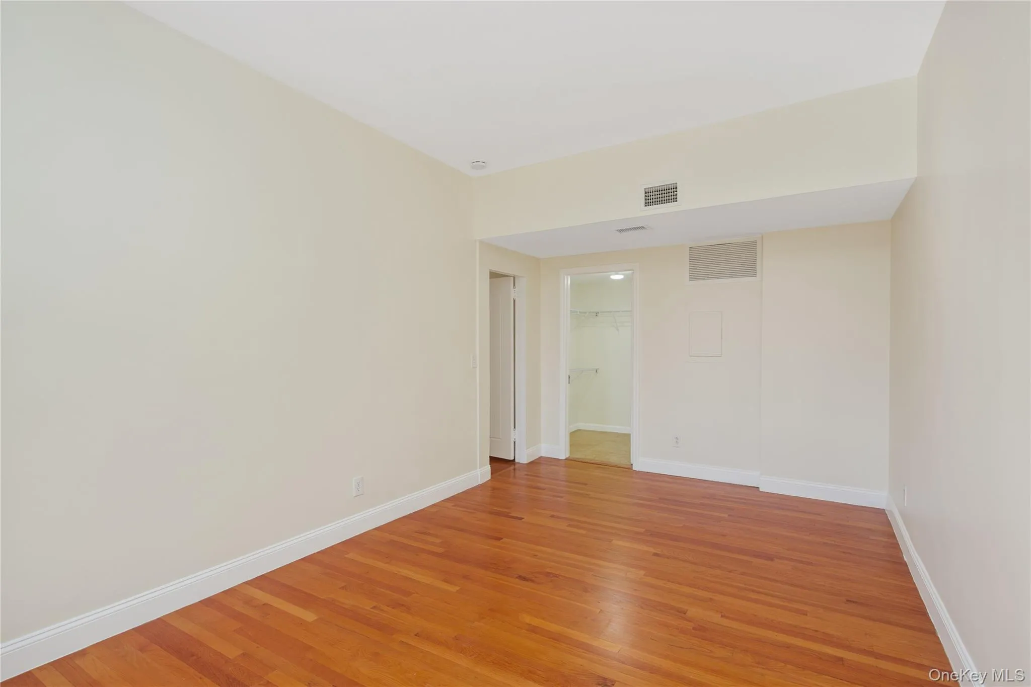 Empty room with baseboards and light wood-type flooring Empty room with baseboards and light wood-type flooring