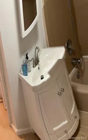 Bathroom with light wood-style floors, vanity, and shower / bathtub combination Bathroom with light wood-style floors, vanity, and shower / bathtub combination