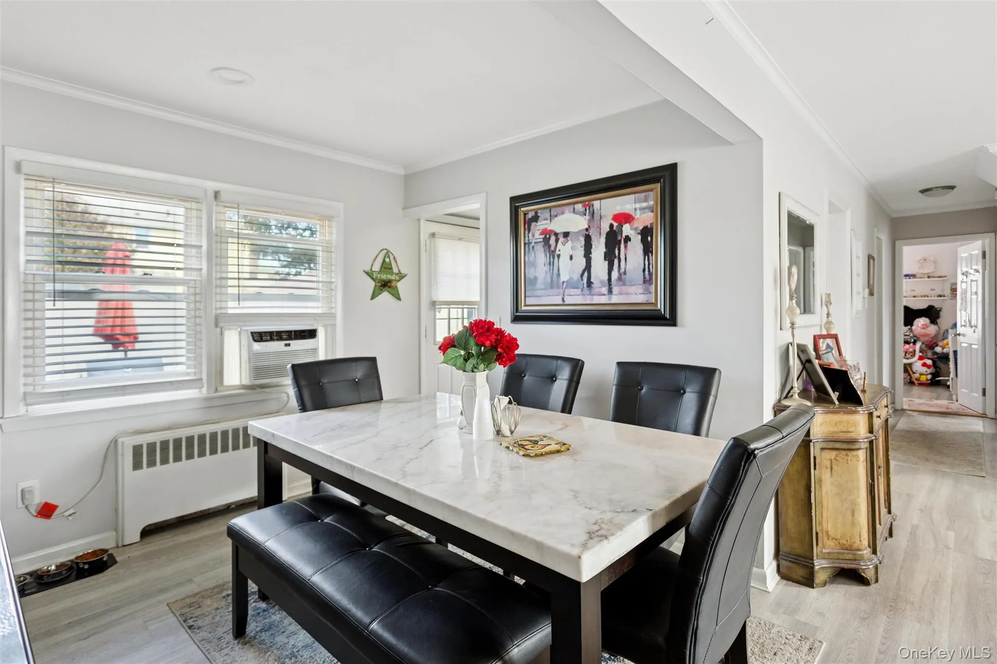 Dining room with crown molding, radiator heating unit, light wood finished floors, and cooling unit Dining room with crown molding, radiator heating unit, light wood finished floors, and cooling unit