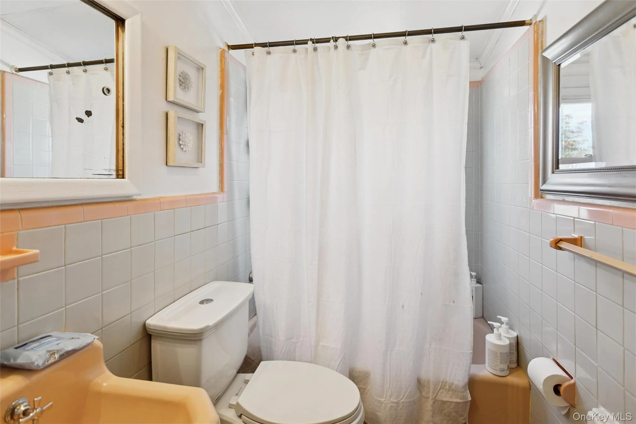 Bathroom with tile walls, crown molding, and shower / tub combo with curtain Bathroom with tile walls, crown molding, and shower / tub combo with curtain