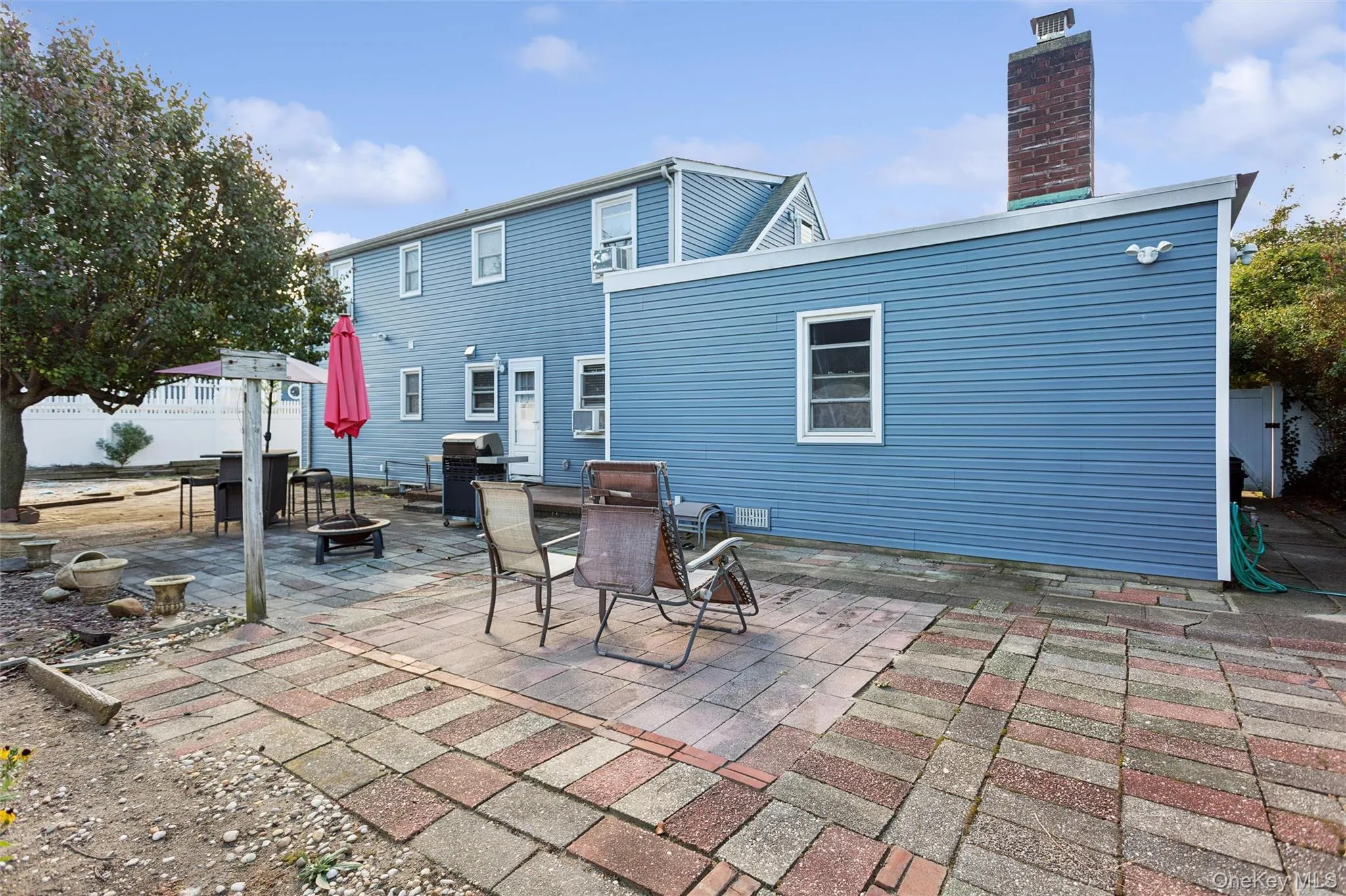 Back of house featuring a patio, a chimney, and an outdoor fire pit Back of house featuring a patio, a chimney, and an outdoor fire pit
