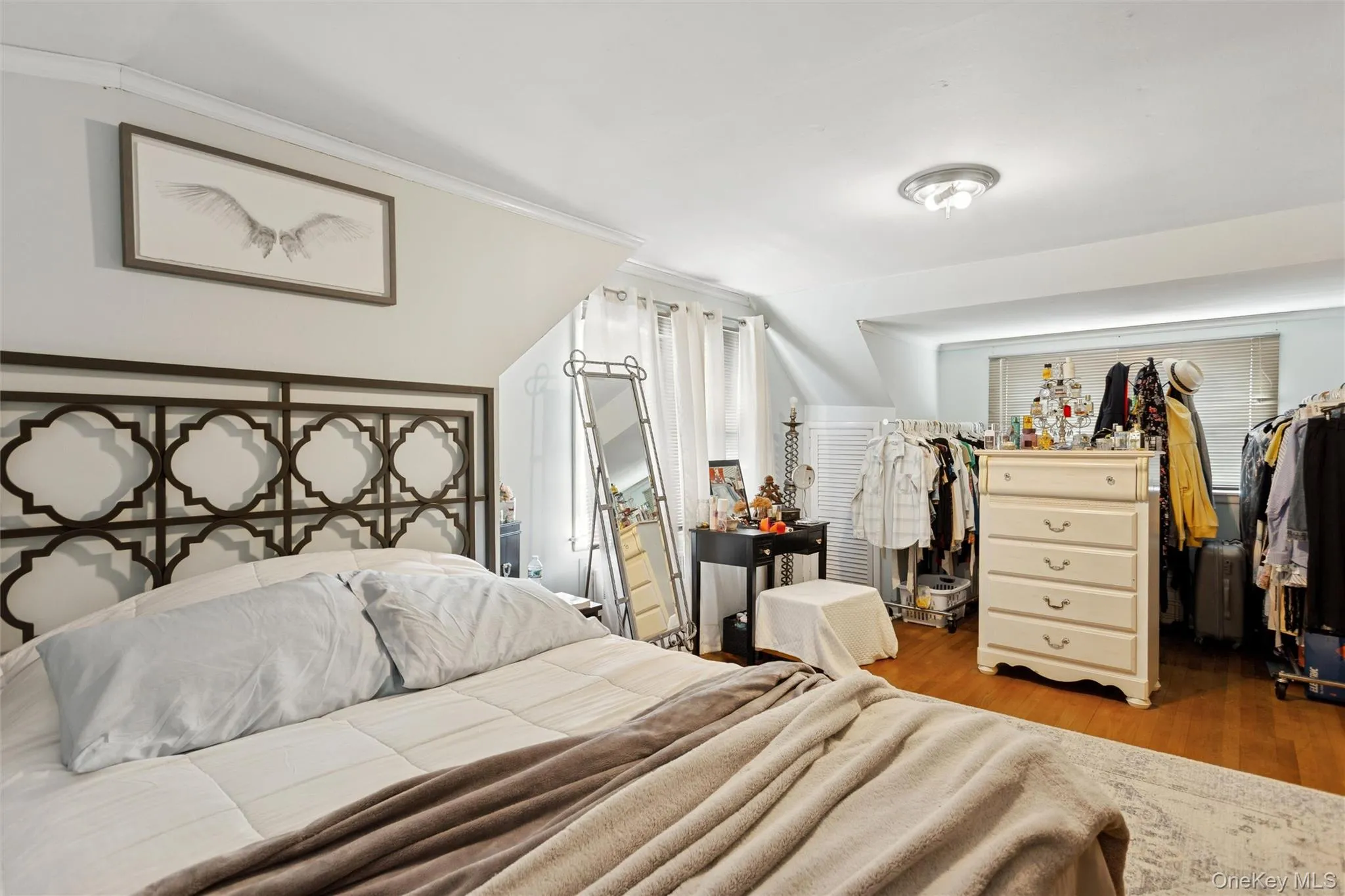 Bedroom with wood finished floors, a closet, and crown molding Bedroom with wood finished floors, a closet, and crown molding