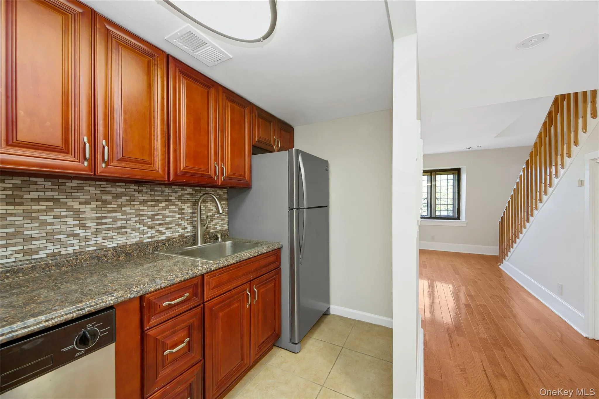 Kitchen featuring stainless steel appliances, backsplash, light wood-type flooring, and reddish brown cabinets Kitchen featuring stainless steel appliances, backsplash, light wood-type flooring, and reddish brown cabinets
