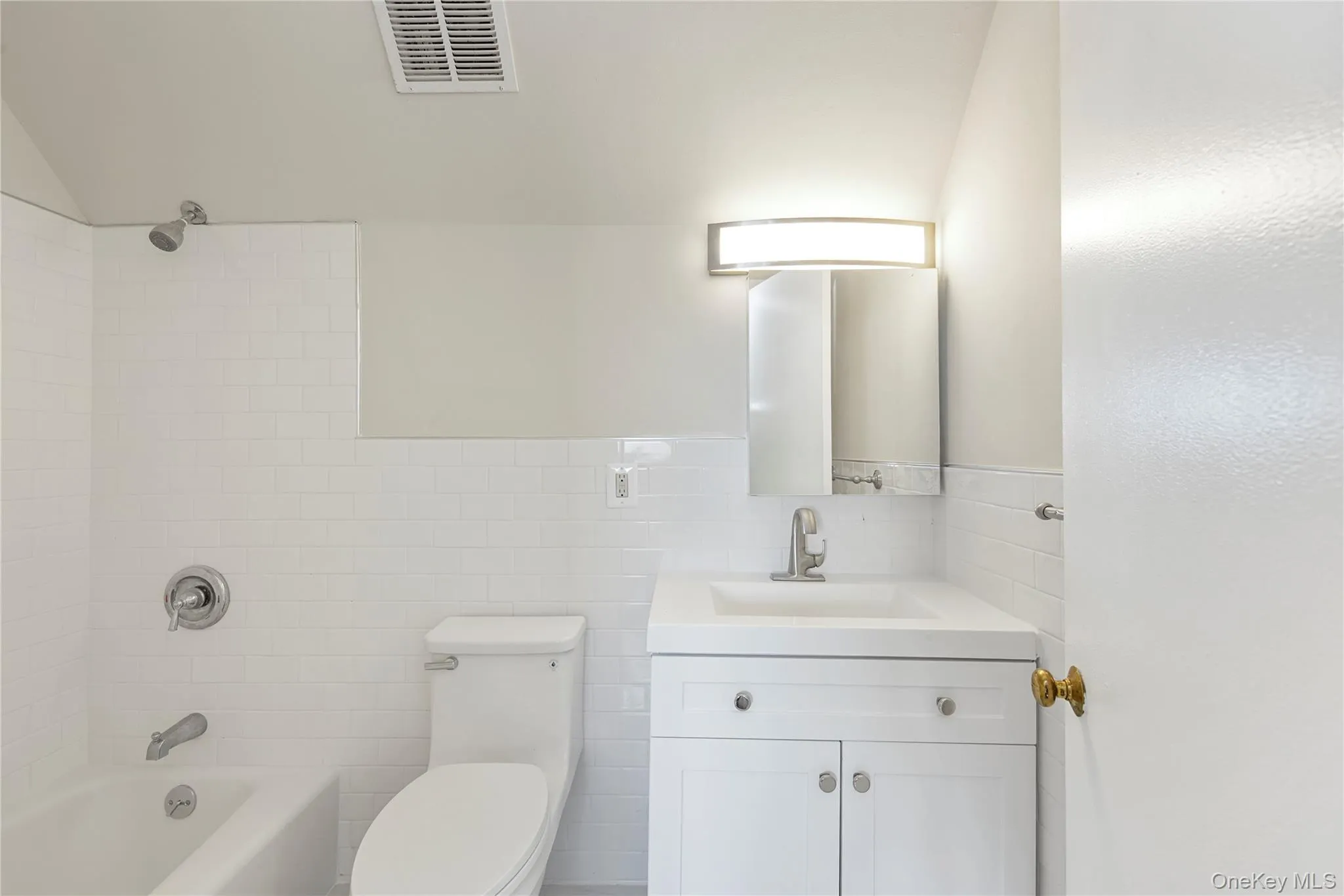 Full bathroom featuring tub / shower combination, vanity, and tile walls Full bathroom featuring tub / shower combination, vanity, and tile walls