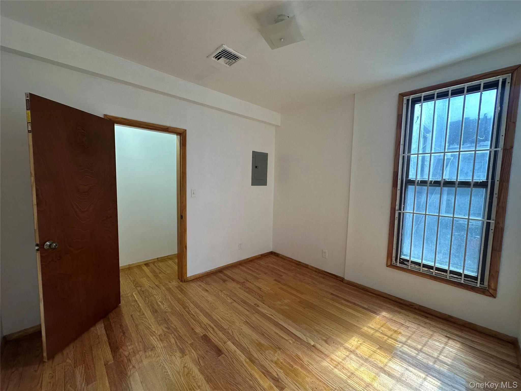 Unfurnished room with light wood-style floors and electric panel Unfurnished room with light wood-style floors and electric panel