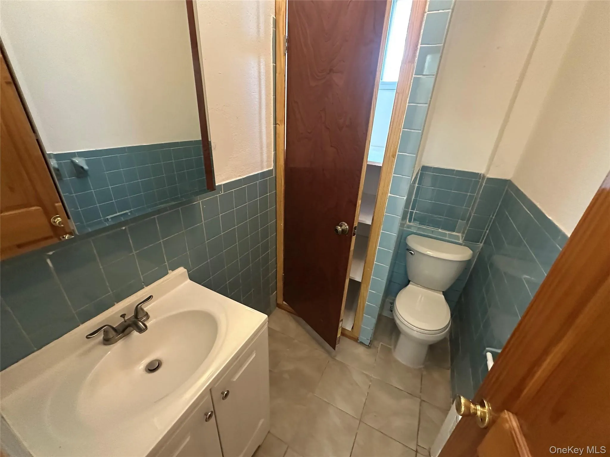 Bathroom with vanity, light tile patterned floors, tile walls, and wainscoting Bathroom with vanity, light tile patterned floors, tile walls, and wainscoting