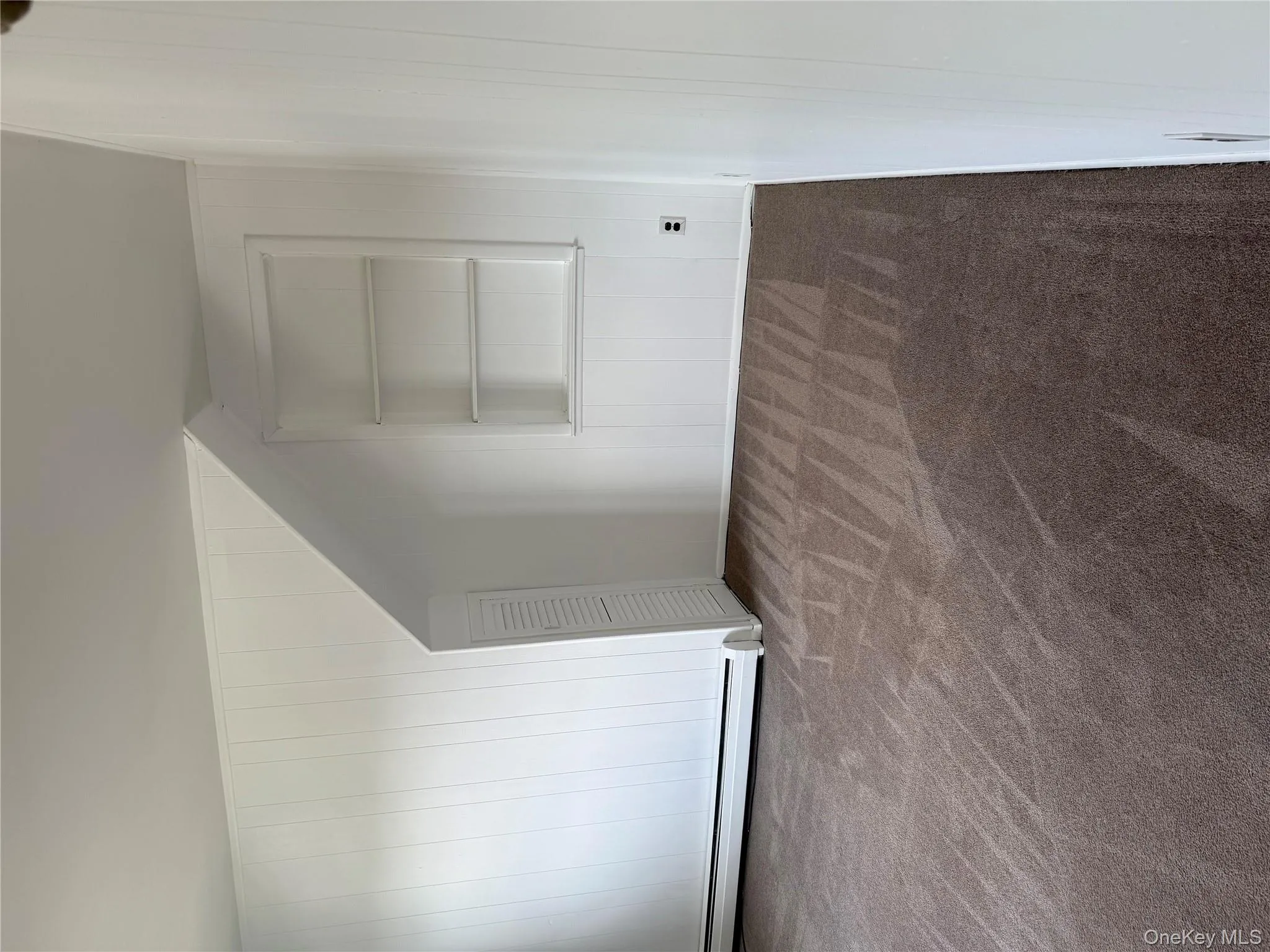 Bonus room with wood walls, dark colored carpet, a baseboard radiator, and built in shelves Bonus room with wood walls, dark colored carpet, a baseboard radiator, and built in shelves