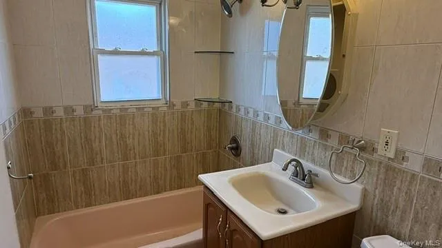 Bathroom with vanity, shower / washtub combination, and tile walls Bathroom with vanity, shower / washtub combination, and tile walls