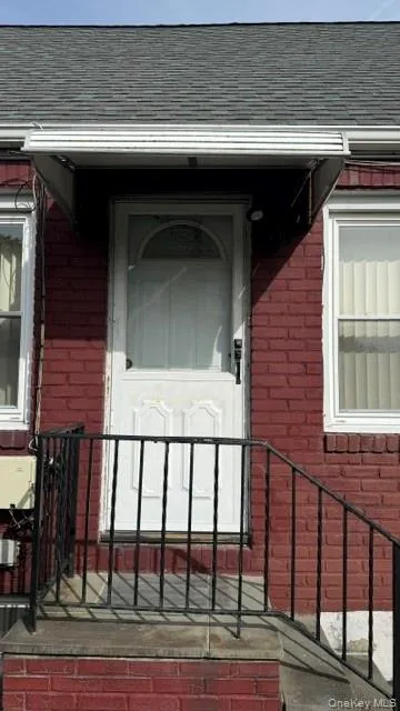 Entrance to property featuring brick siding and roof with shingles Entrance to property featuring brick siding and roof with shingles