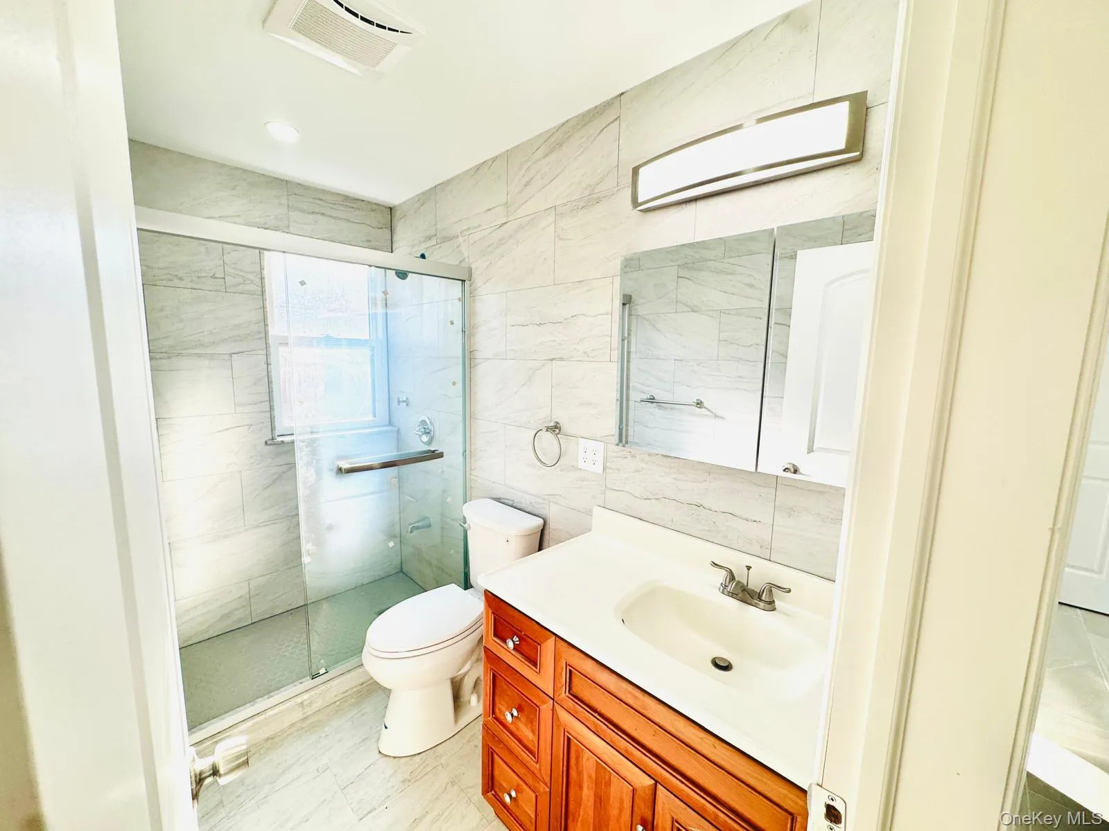 Full bathroom with vanity, a shower stall, and tile walls Full bathroom with vanity, a shower stall, and tile walls