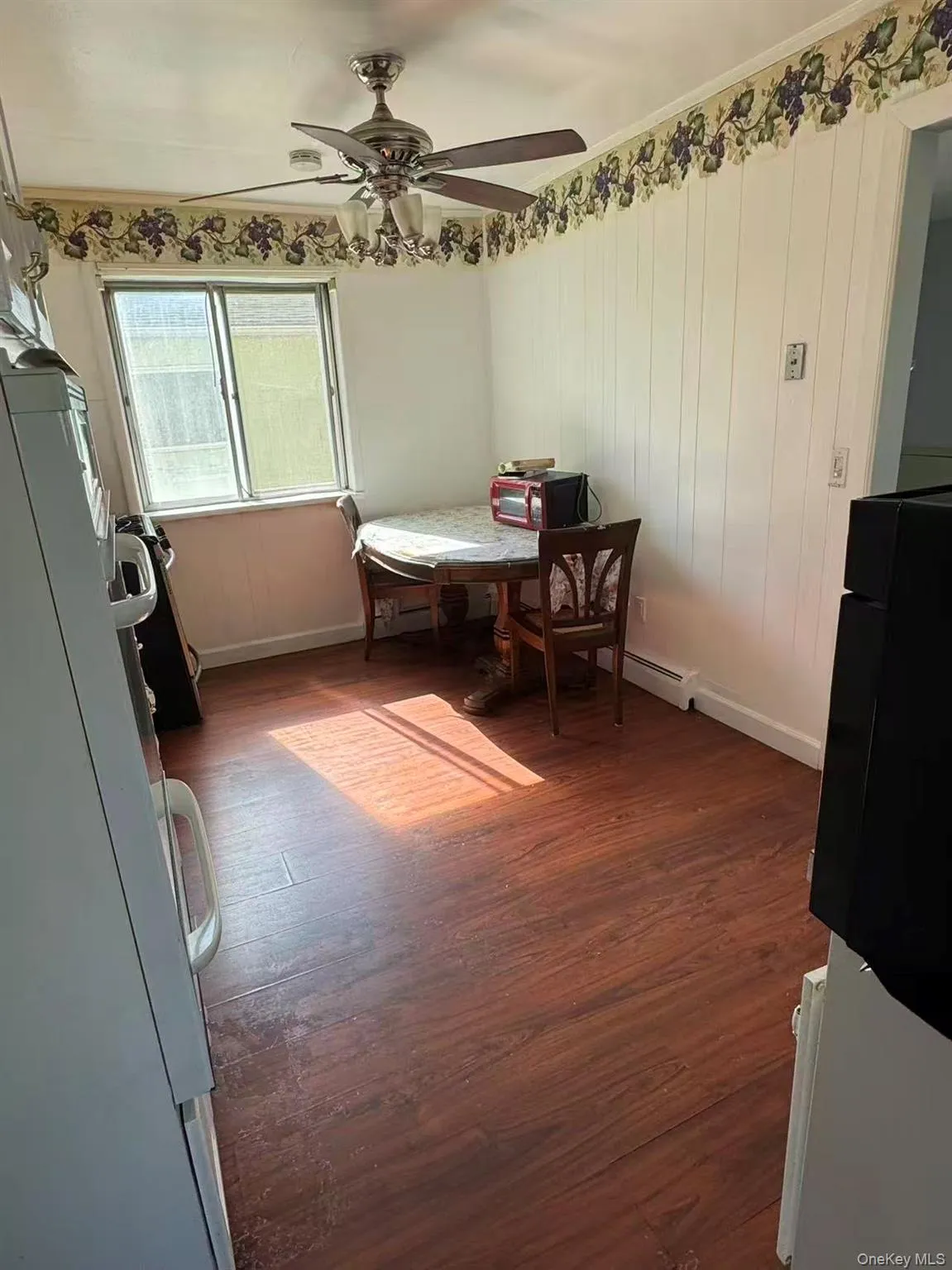 Dining area with dark wood finished floors, a baseboard heating unit, and a ceiling fan Dining area with dark wood finished floors, a baseboard heating unit, and a ceiling fan