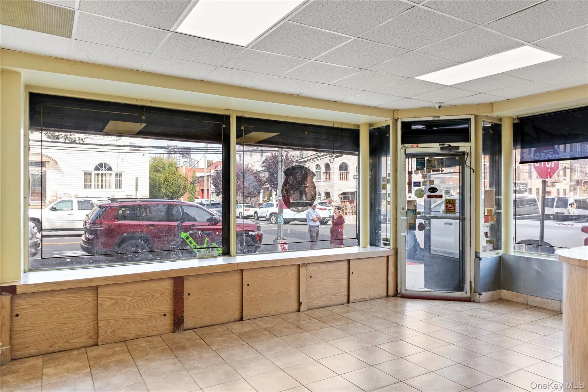 Empty room with healthy amount of natural light, light tile patterned floors, and a drop ceiling Empty room with healthy amount of natural light, light tile patterned floors, and a drop ceiling