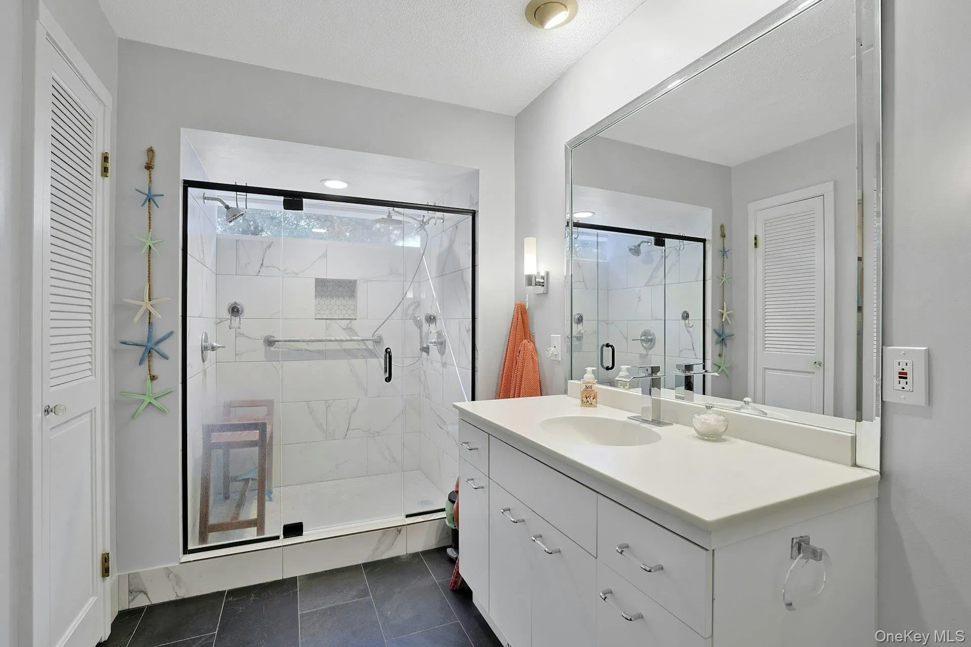 Primary bathroom with walk-in shower, vanity, dark tile patterned floors, and 2 closets. Primary bathroom with walk-in shower, vanity, dark tile patterned floors, and 2 closets.