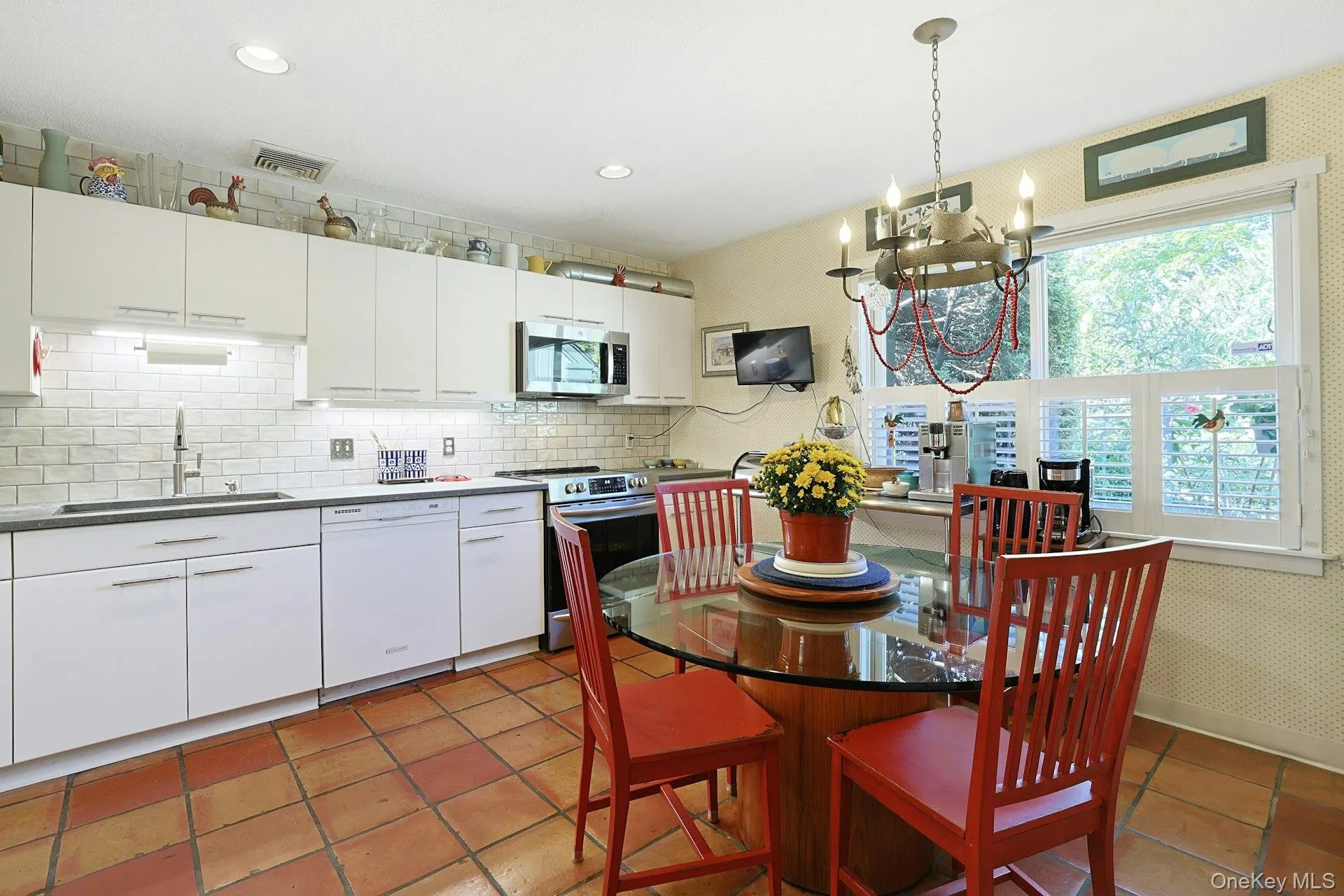 Kitchen with stainless steel appliances, backsplash, white cabinetry, terracotta tile floors, and recessed lighting Kitchen with stainless steel appliances, backsplash, white cabinetry, terracotta tile floors, and recessed lighting