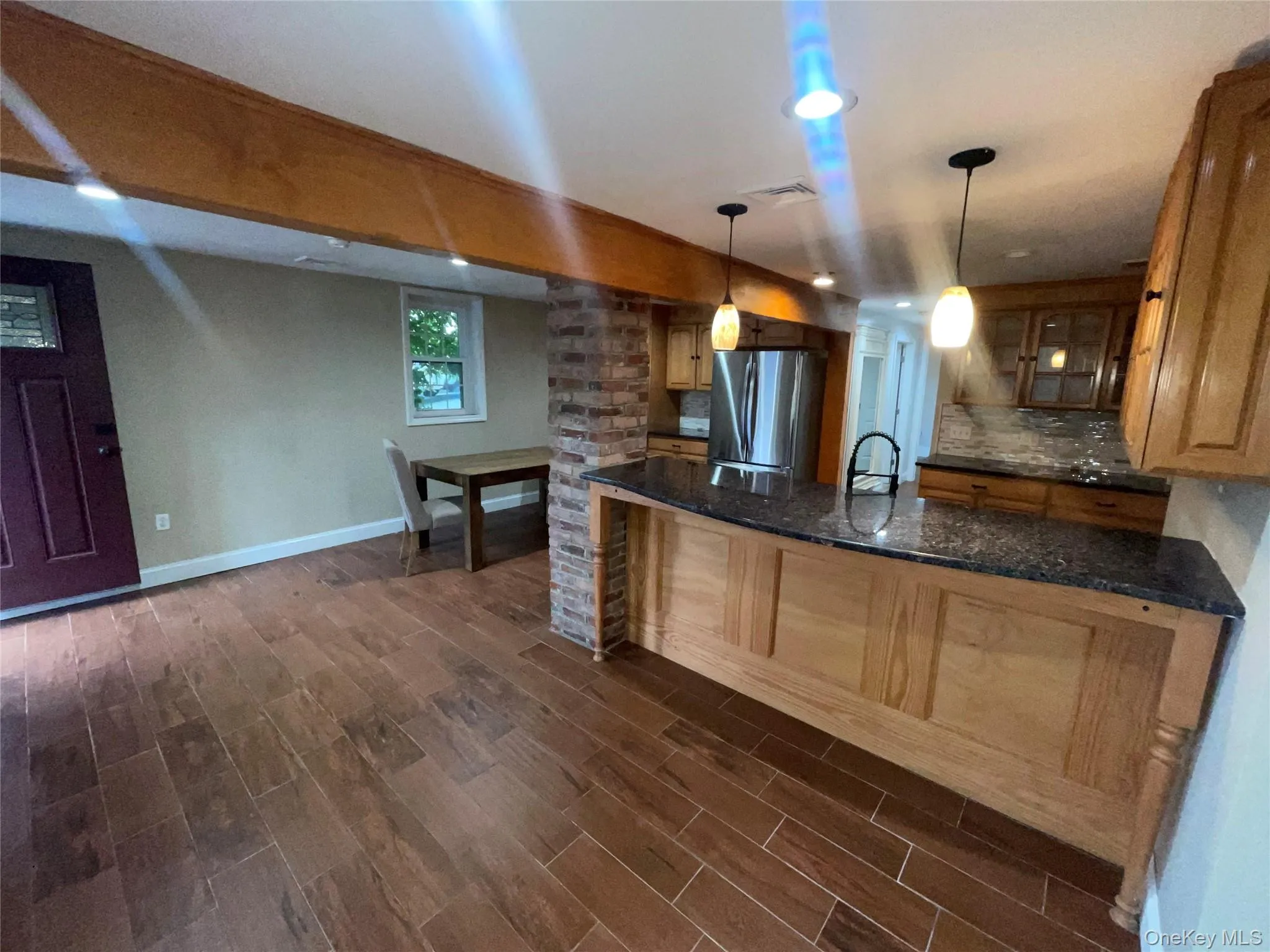 Kitchen with glass insert cabinets, freestanding refrigerator, a peninsula, backsplash, and dark wood finished floors Kitchen with glass insert cabinets, freestanding refrigerator, a peninsula, backsplash, and dark wood finished floors