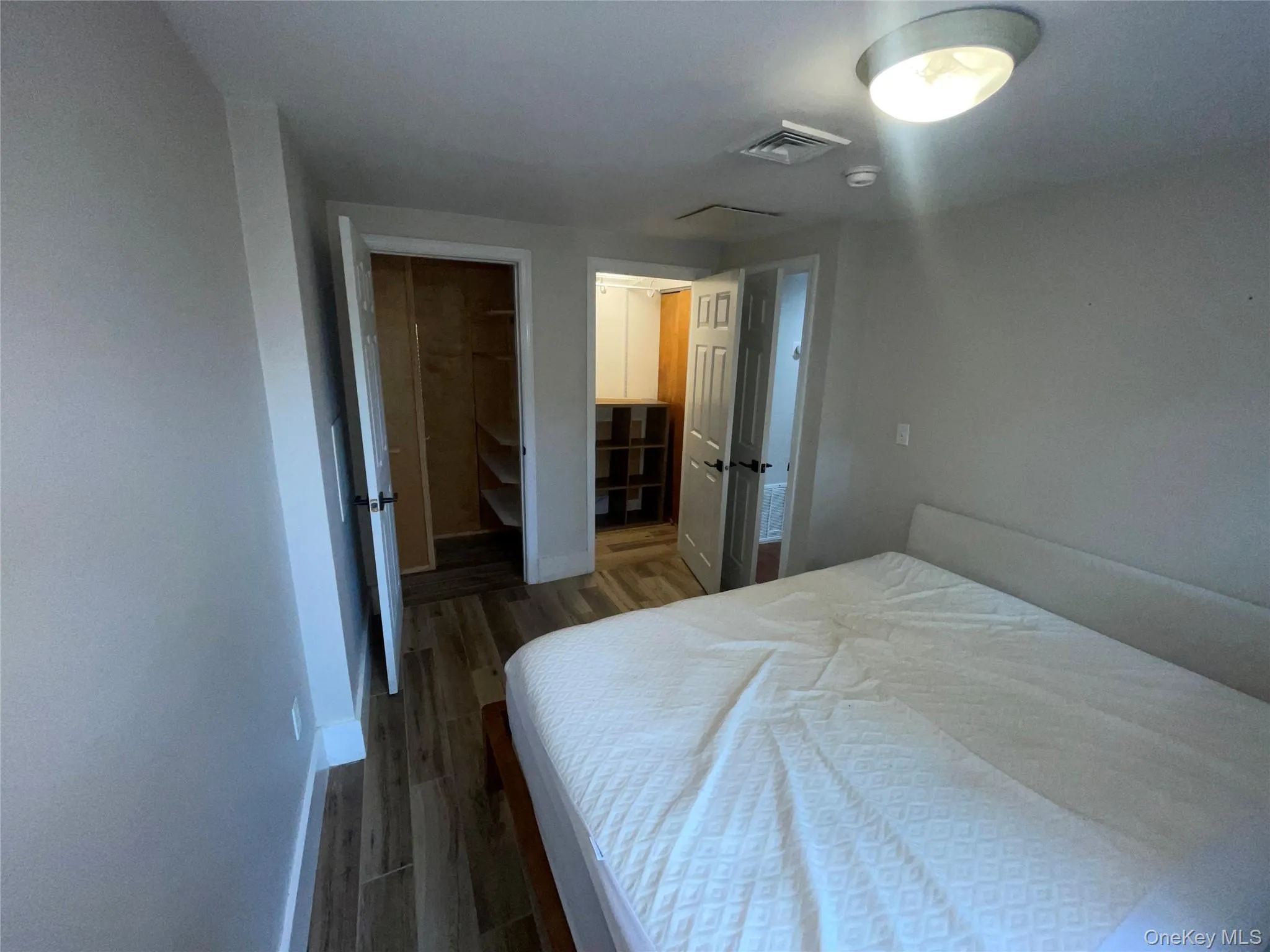 Bedroom featuring dark wood-style floors and a walk in closet Bedroom featuring dark wood-style floors and a walk in closet
