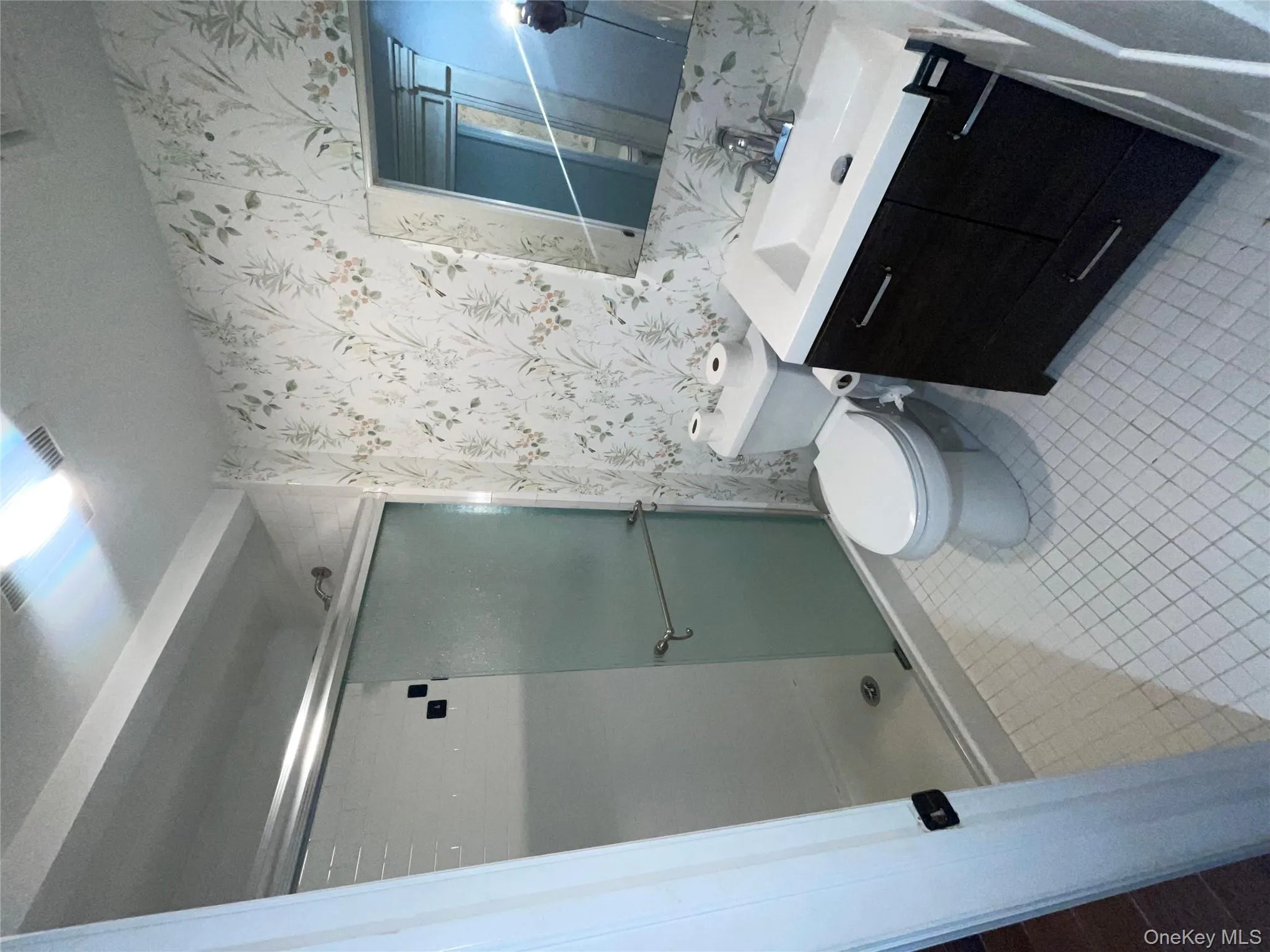 Full bathroom featuring wallpapered walls, vanity, a shower stall, and light tile patterned flooring Full bathroom featuring wallpapered walls, vanity, a shower stall, and light tile patterned flooring