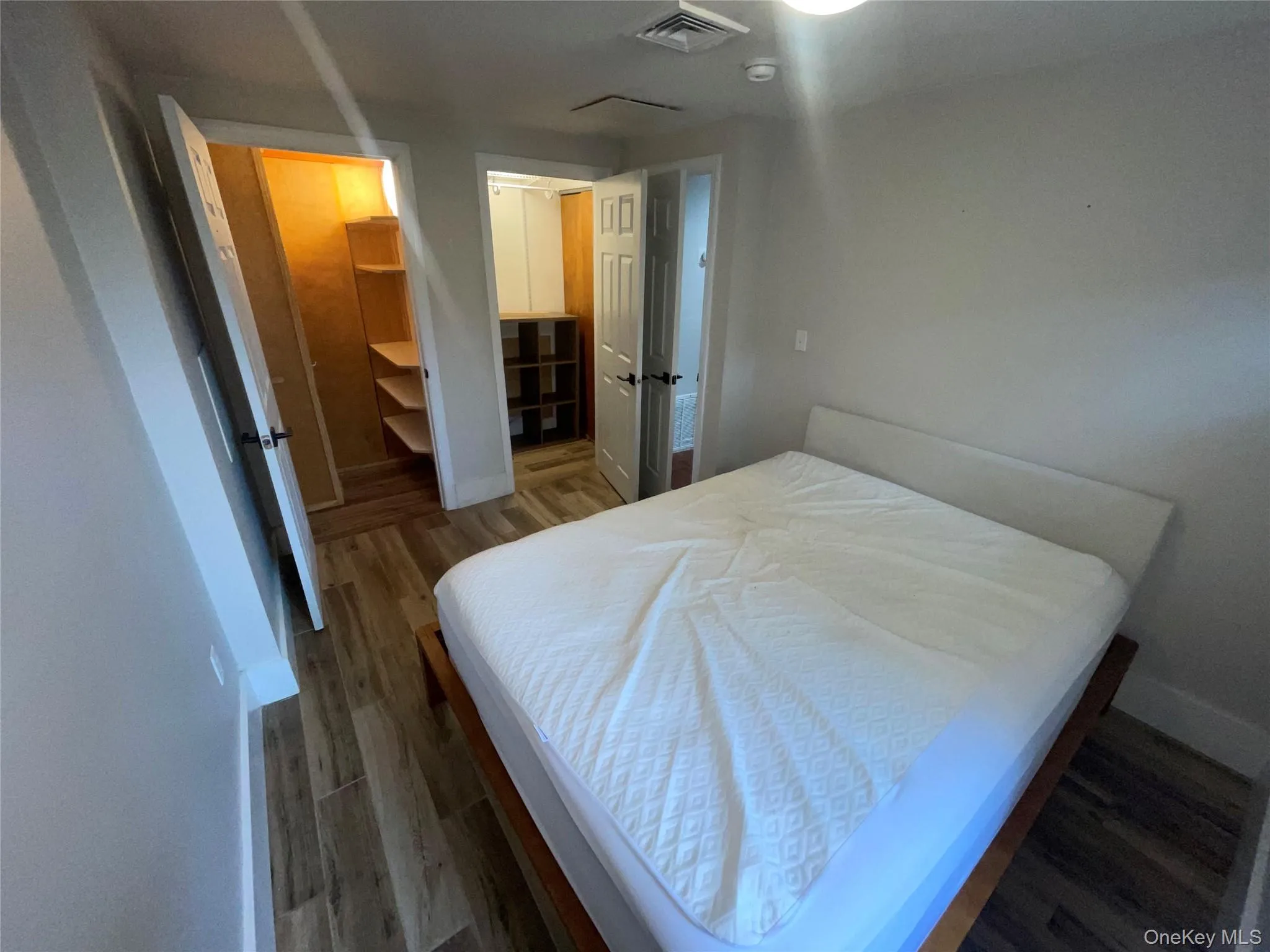Bedroom with dark wood-type flooring and a spacious closet Bedroom with dark wood-type flooring and a spacious closet
