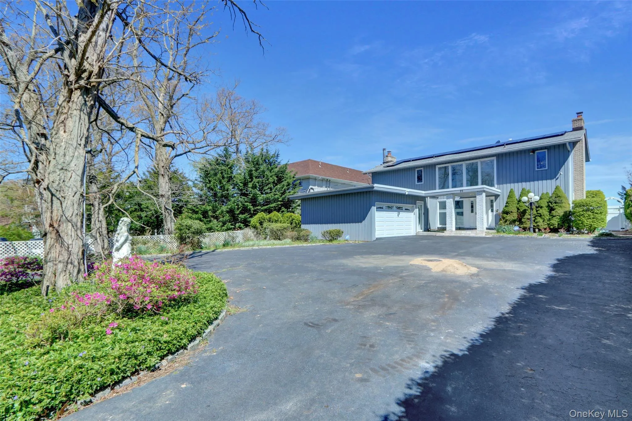 Traditional-style home with a chimney, roof mounted solar panels, asphalt driveway, and an attached garage Traditional-style home with a chimney, roof mounted solar panels, asphalt driveway, and an attached garage