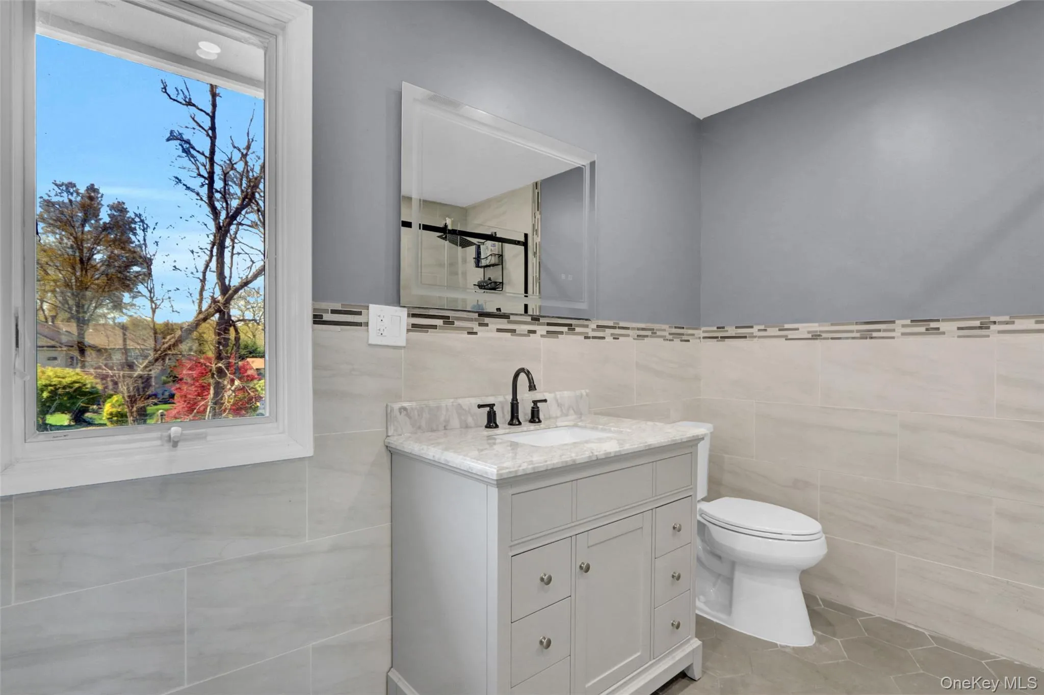 Bathroom featuring vanity, tile walls, a stall shower, and light tile patterned floors Bathroom featuring vanity, tile walls, a stall shower, and light tile patterned floors