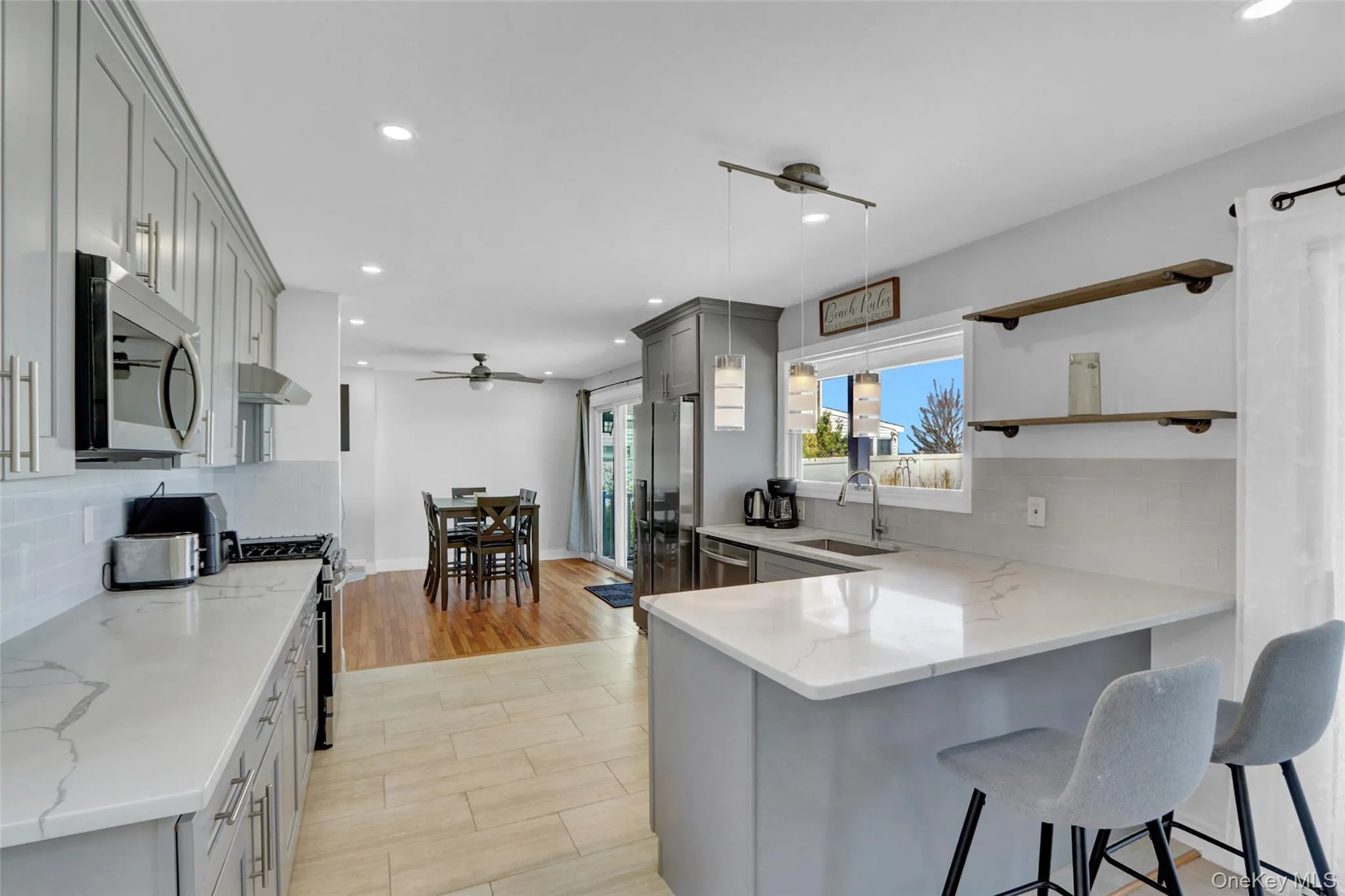 Kitchen featuring backsplash, gray cabinets, recessed lighting, light stone countertops, and a peninsula Kitchen featuring backsplash, gray cabinets, recessed lighting, light stone countertops, and a peninsula