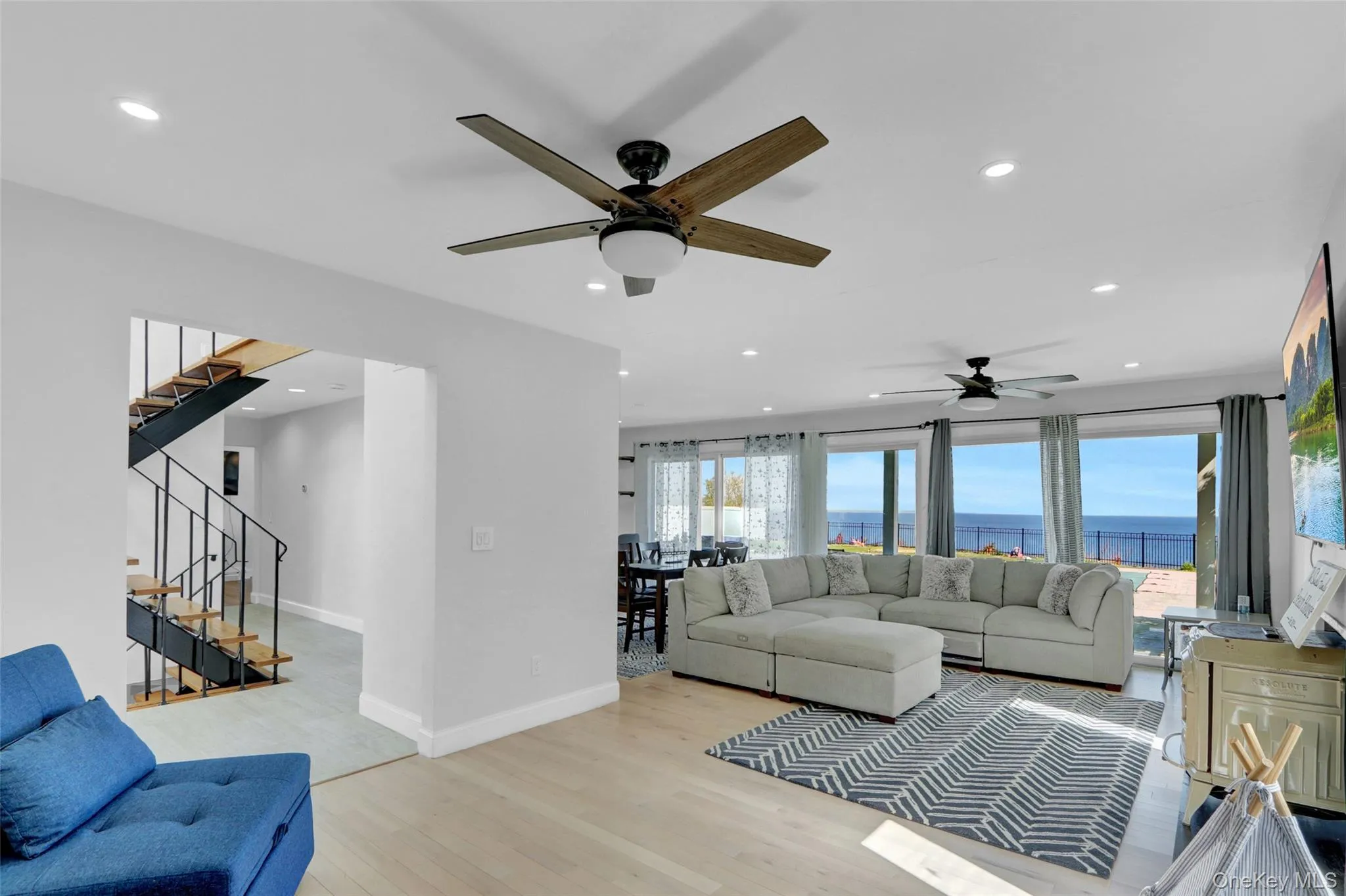 Living room featuring light wood finished floors, recessed lighting, and stairway Living room featuring light wood finished floors, recessed lighting, and stairway