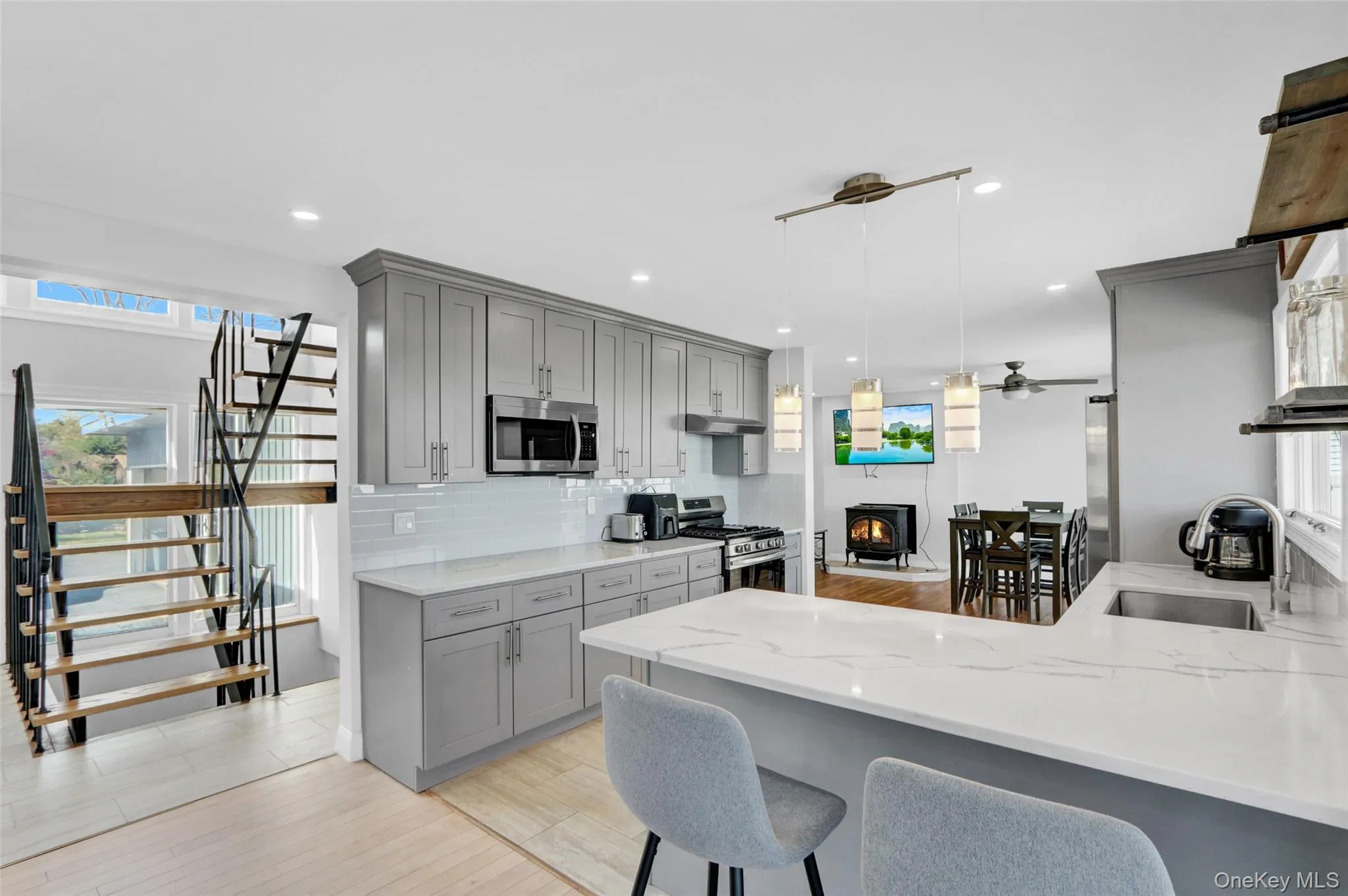 Kitchen with gray cabinets, light stone countertops, light wood-style flooring, and recessed lighting Kitchen with gray cabinets, light stone countertops, light wood-style flooring, and recessed lighting