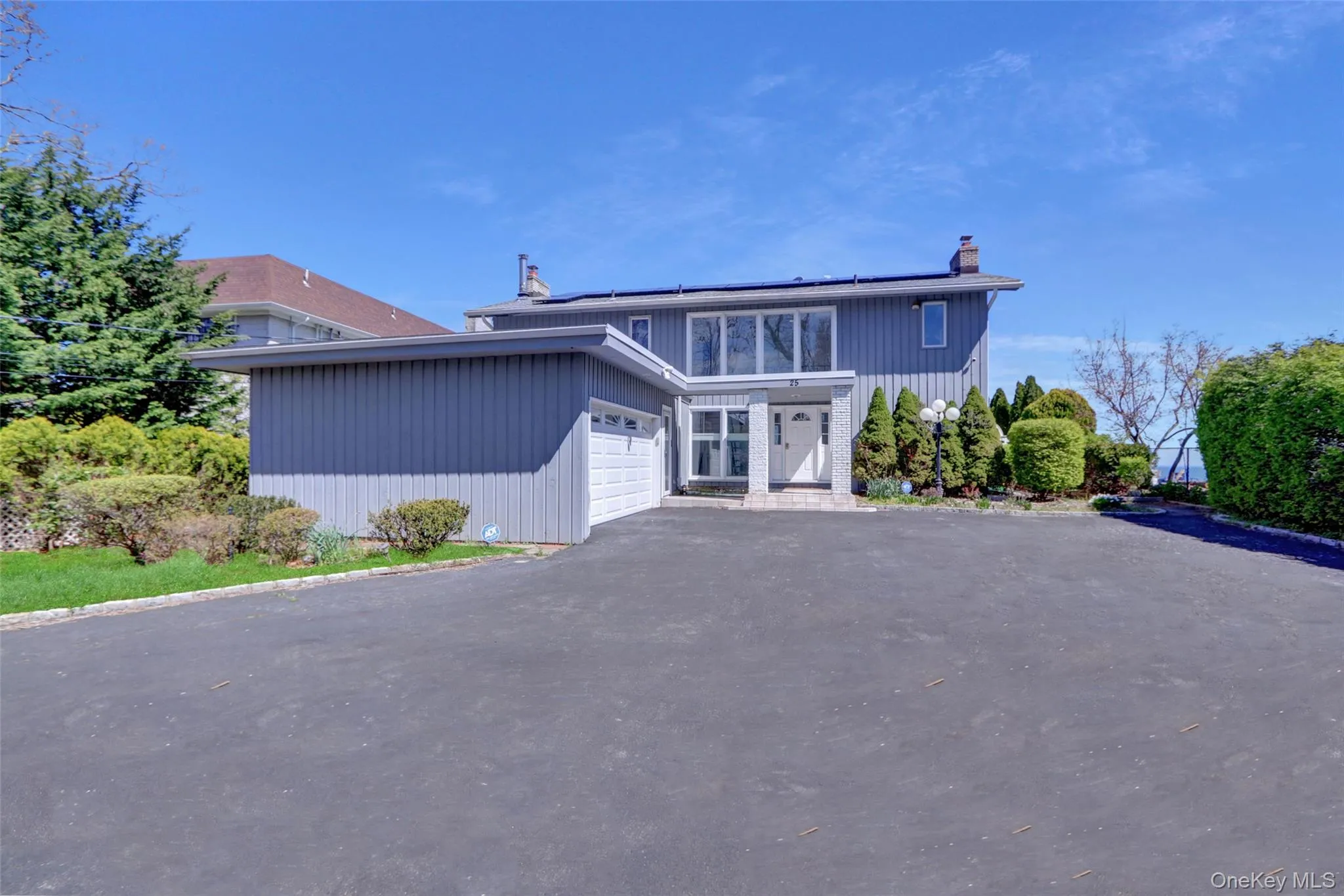 View of front of property with a chimney, asphalt driveway, solar panels, and an attached garage View of front of property with a chimney, asphalt driveway, solar panels, and an attached garage