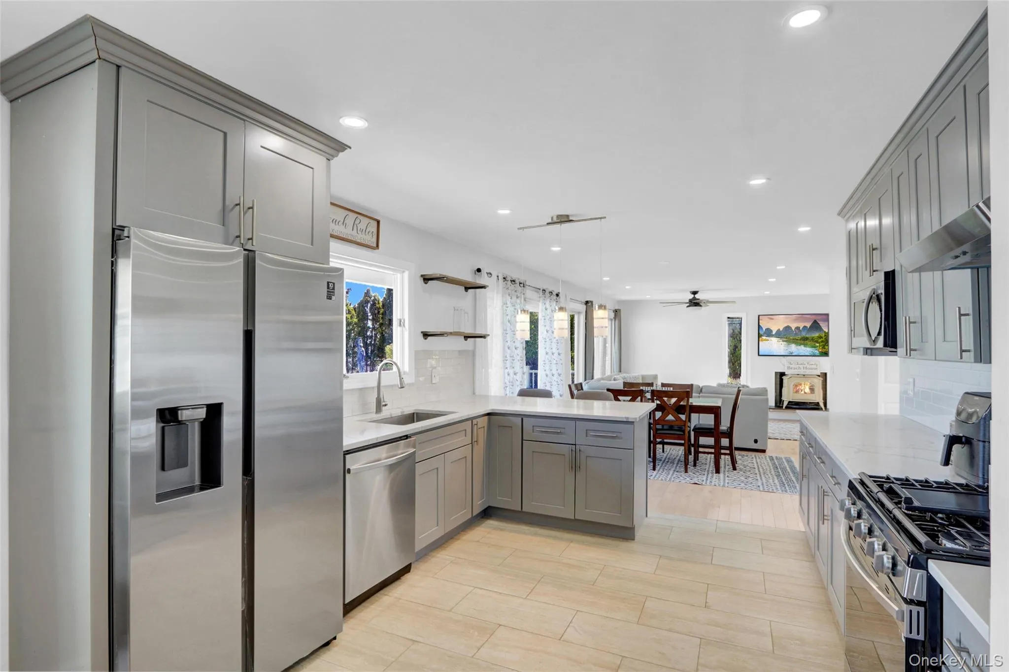 Kitchen featuring decorative backsplash, stainless steel appliances, gray cabinetry, recessed lighting, and open shelves Kitchen featuring decorative backsplash, stainless steel appliances, gray cabinetry, recessed lighting, and open shelves