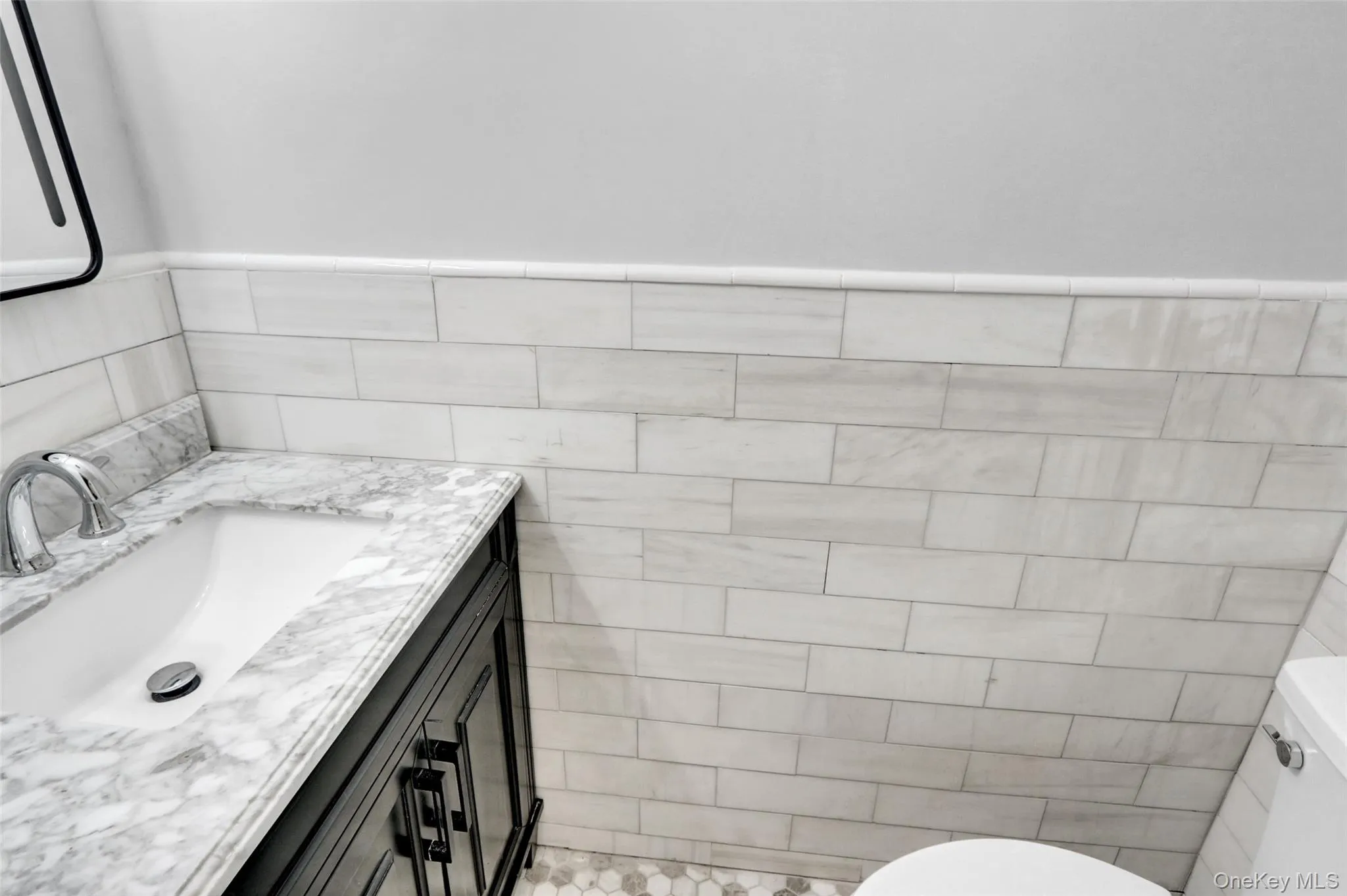 Half bathroom with vanity, tile walls, and a wainscoted wall Half bathroom with vanity, tile walls, and a wainscoted wall