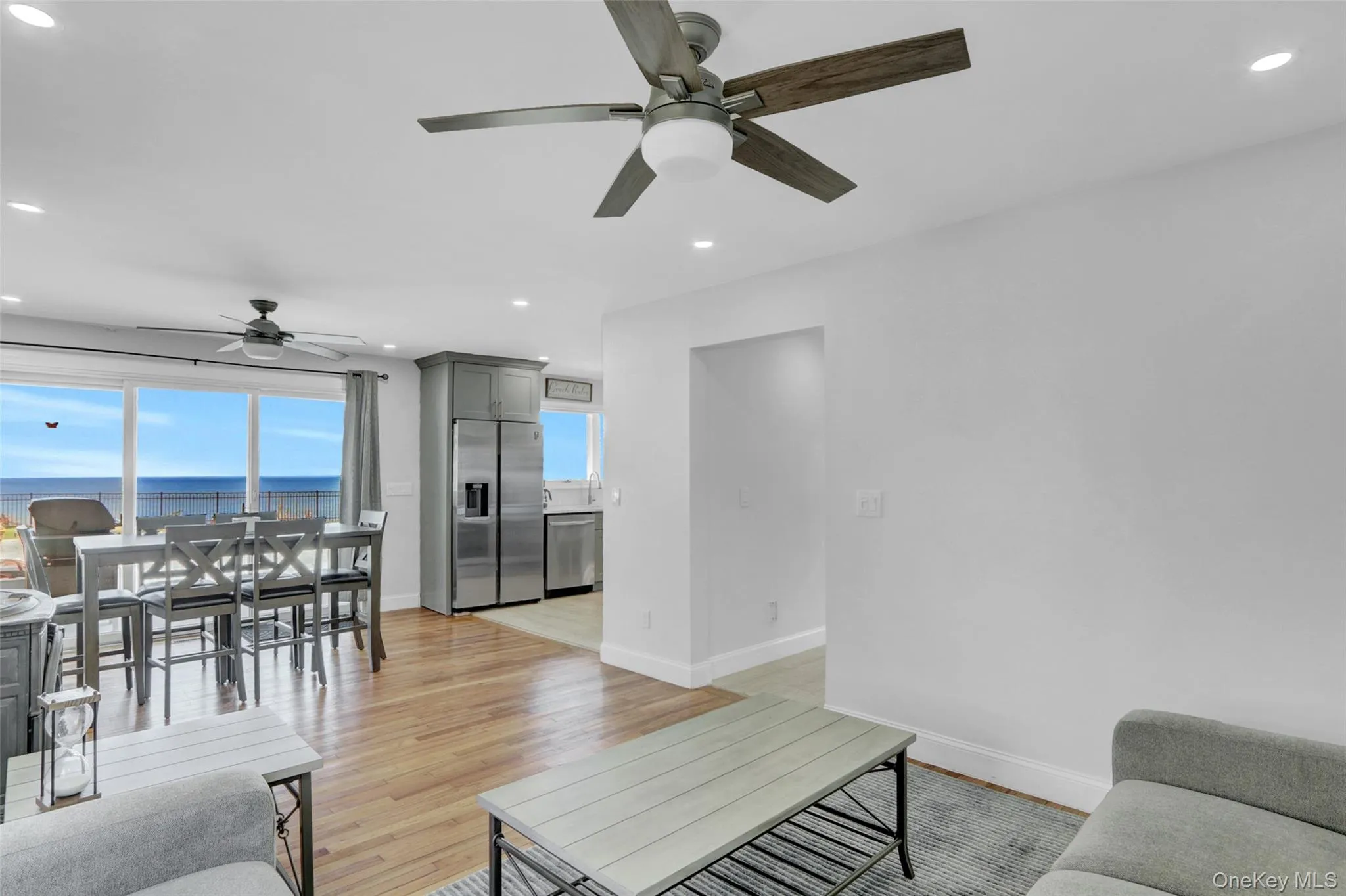 Living room with recessed lighting, light wood-style flooring, a ceiling fan, and a water view Living room with recessed lighting, light wood-style flooring, a ceiling fan, and a water view