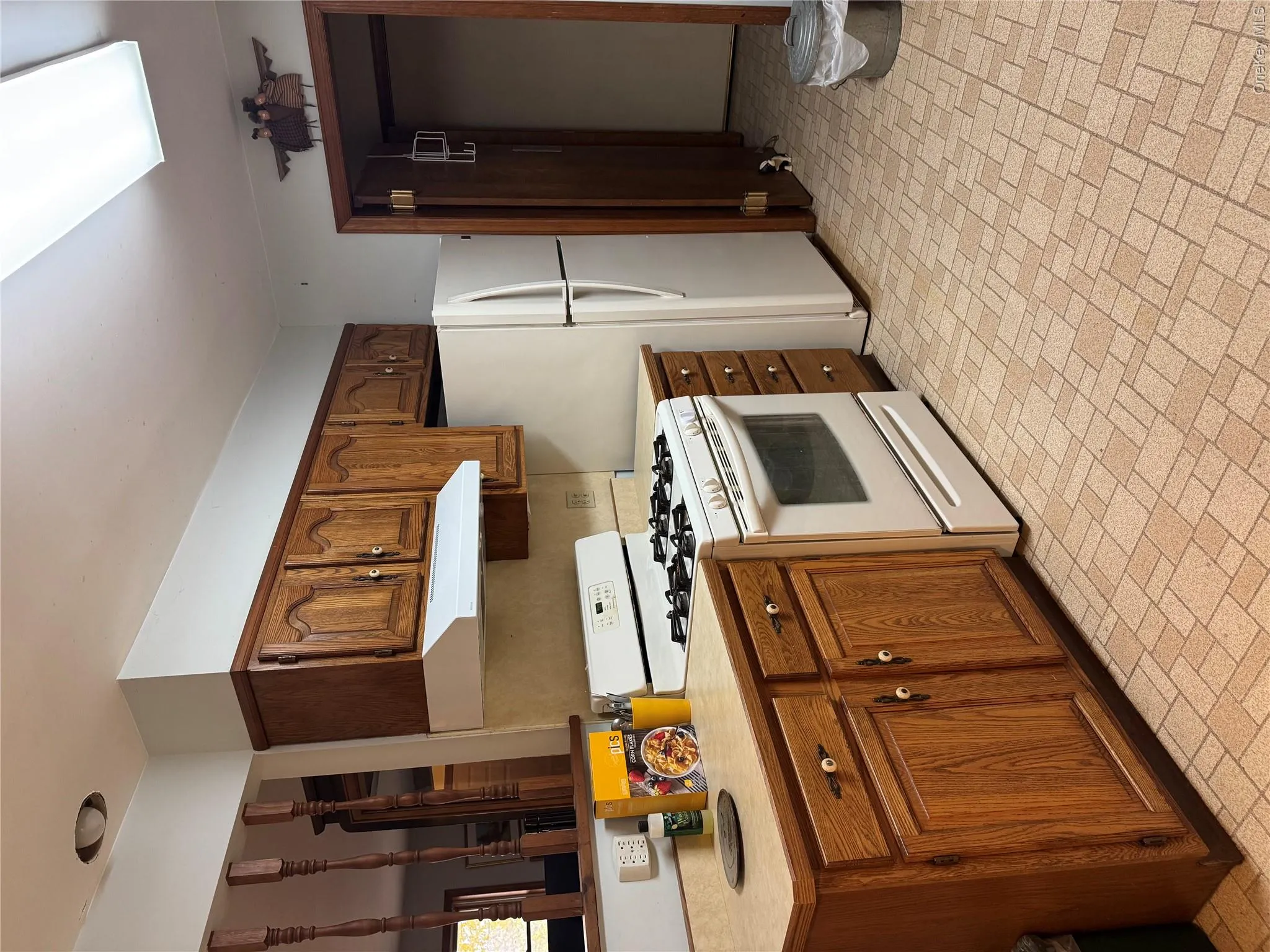 Kitchen with white appliances, brick patterned flooring, light countertops, ventilation hood, and brown cabinets Kitchen with white appliances, brick patterned flooring, light countertops, ventilation hood, and brown cabinets