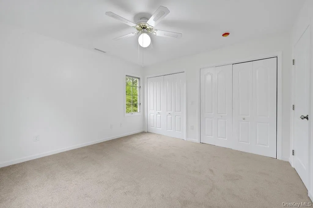 Unfurnished bedroom featuring two closets, carpet floors, and a ceiling fan Unfurnished bedroom featuring two closets, carpet floors, and a ceiling fan