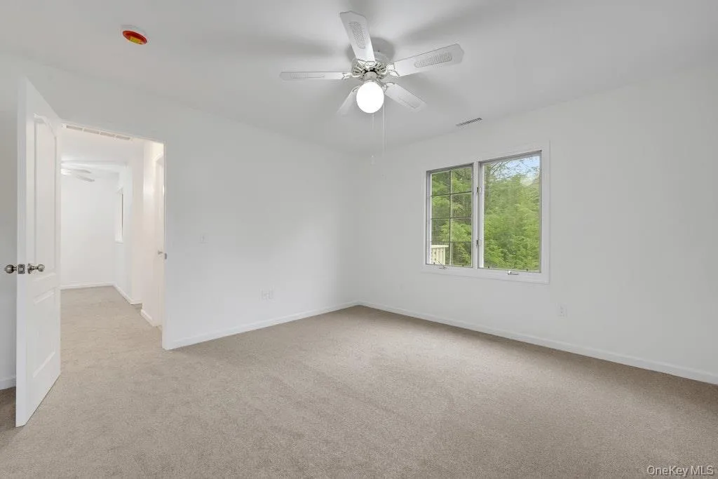 Empty room featuring light colored carpet and ceiling fan Empty room featuring light colored carpet and ceiling fan