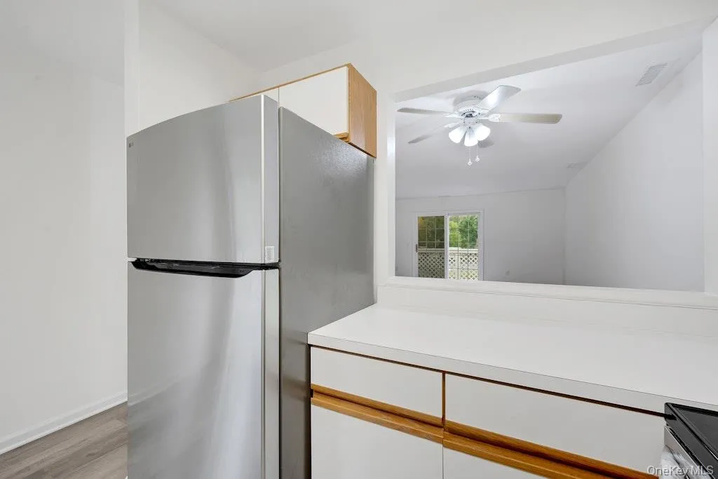 Kitchen with freestanding refrigerator, light countertops, white cabinetry, and light wood-style floors Kitchen with freestanding refrigerator, light countertops, white cabinetry, and light wood-style floors