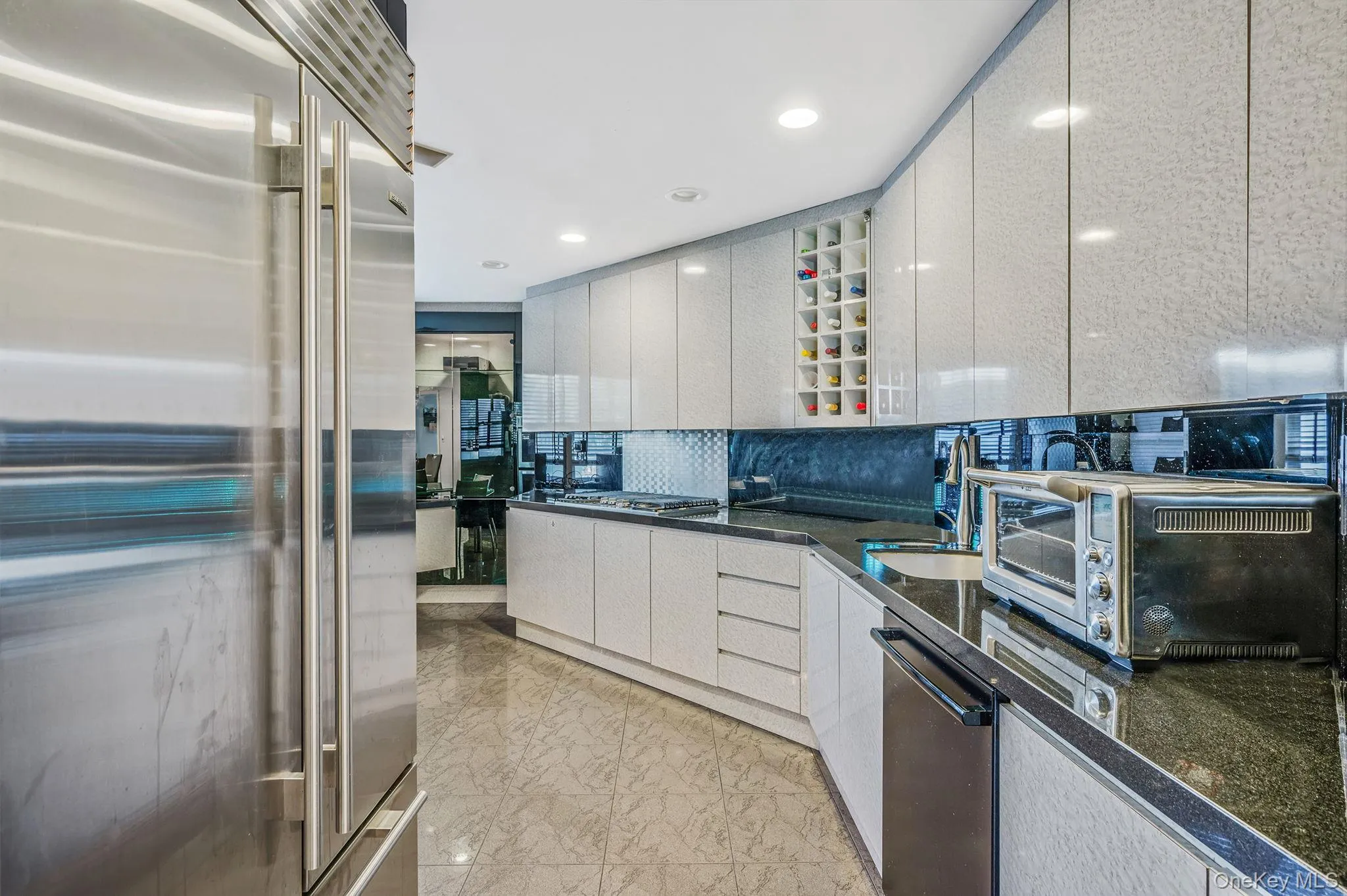 Kitchen with appliances with stainless steel finishes, tasteful backsplash, modern cabinets, recessed lighting, and dark stone counters Kitchen with appliances with stainless steel finishes, tasteful backsplash, modern cabinets, recessed lighting, and dark stone counters