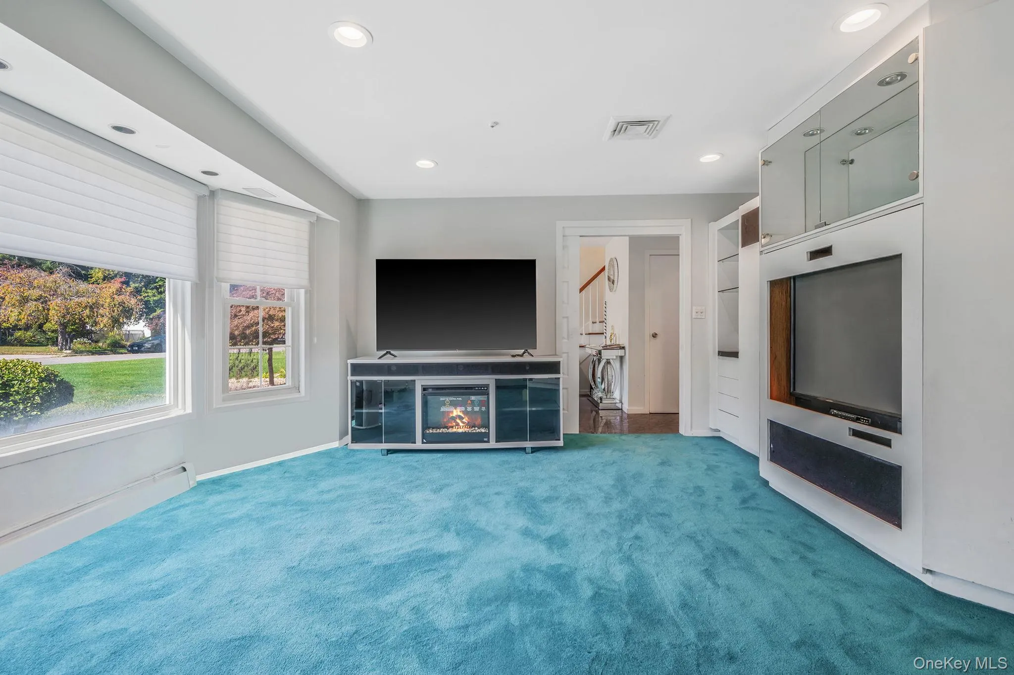 Unfurnished living room with carpet, recessed lighting, and a glass covered fireplace Unfurnished living room with carpet, recessed lighting, and a glass covered fireplace