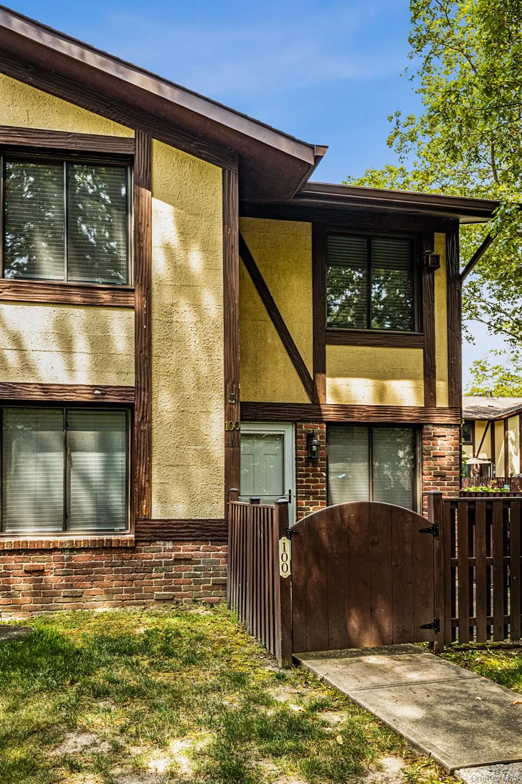 View of property exterior featuring brick siding, a fenced front yard, a gate, and stucco siding View of property exterior featuring brick siding, a fenced front yard, a gate, and stucco siding
