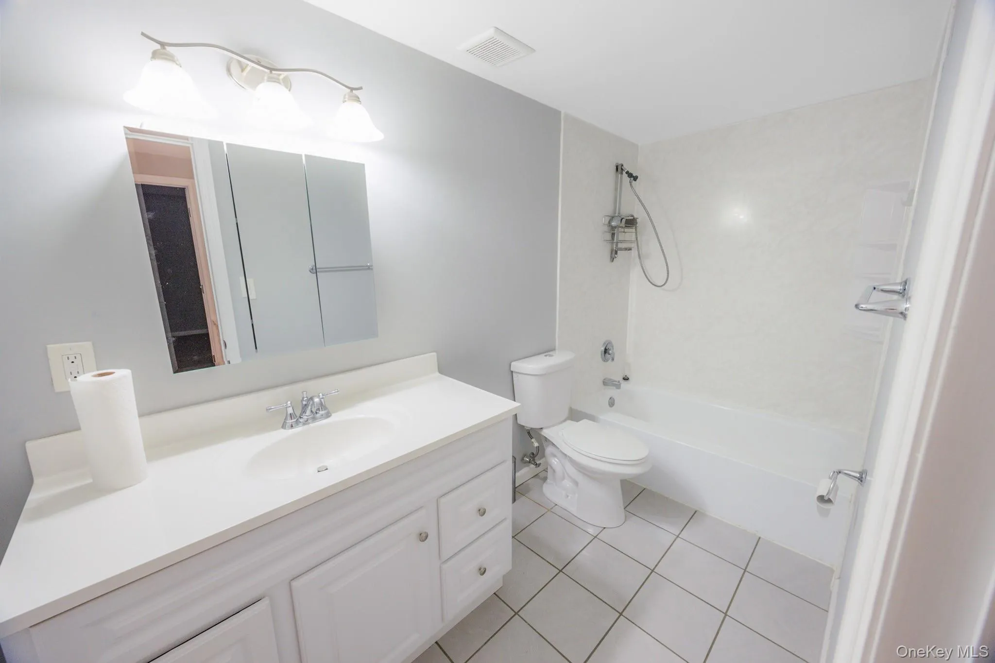 Full bathroom with shower / washtub combination, vanity, and light tile patterned floors Full bathroom with shower / washtub combination, vanity, and light tile patterned floors