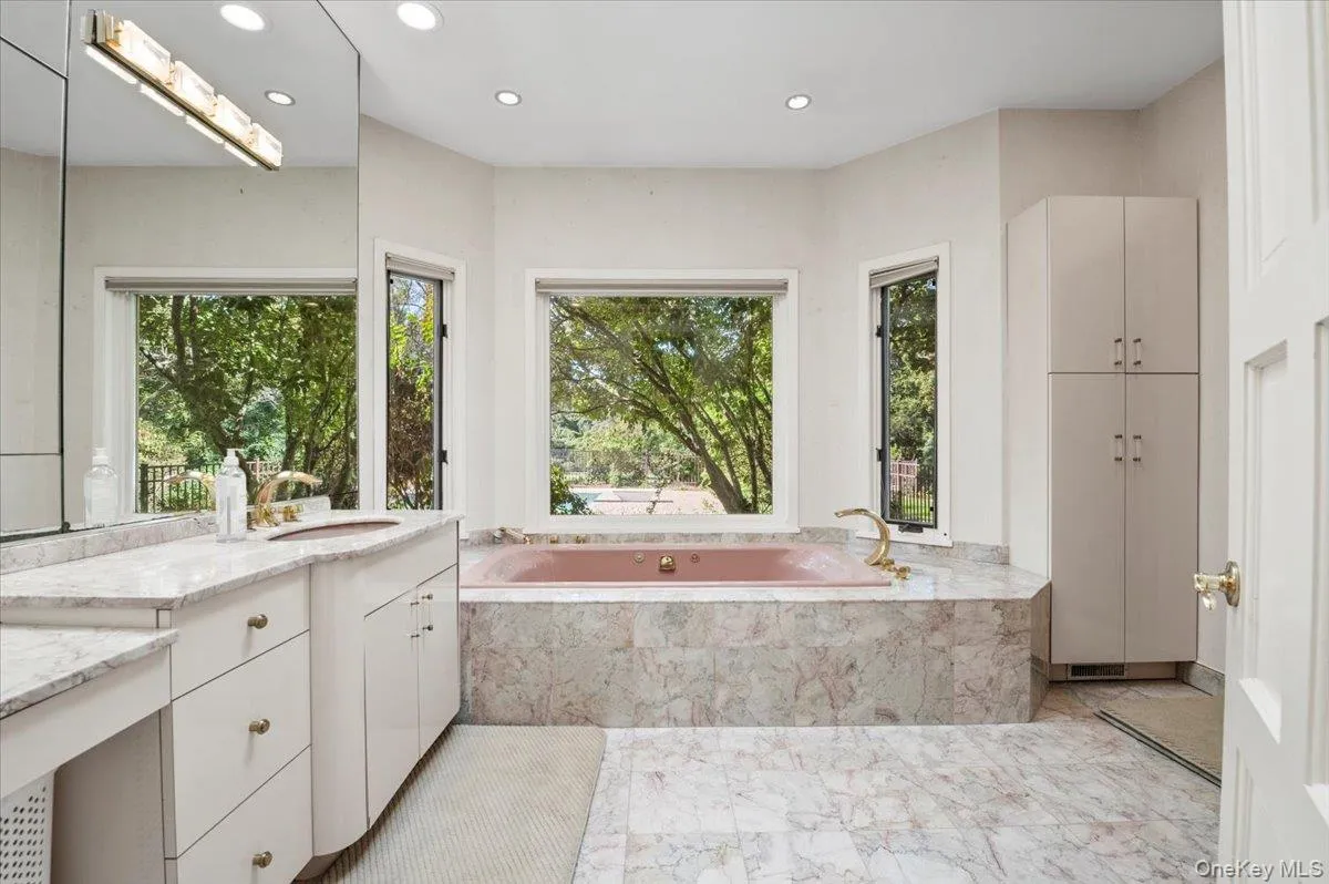 Bathroom featuring recessed lighting, vanity, a bath, light marble finish floors, and healthy amount of natural light Bathroom featuring recessed lighting, vanity, a bath, light marble finish floors, and healthy amount of natural light