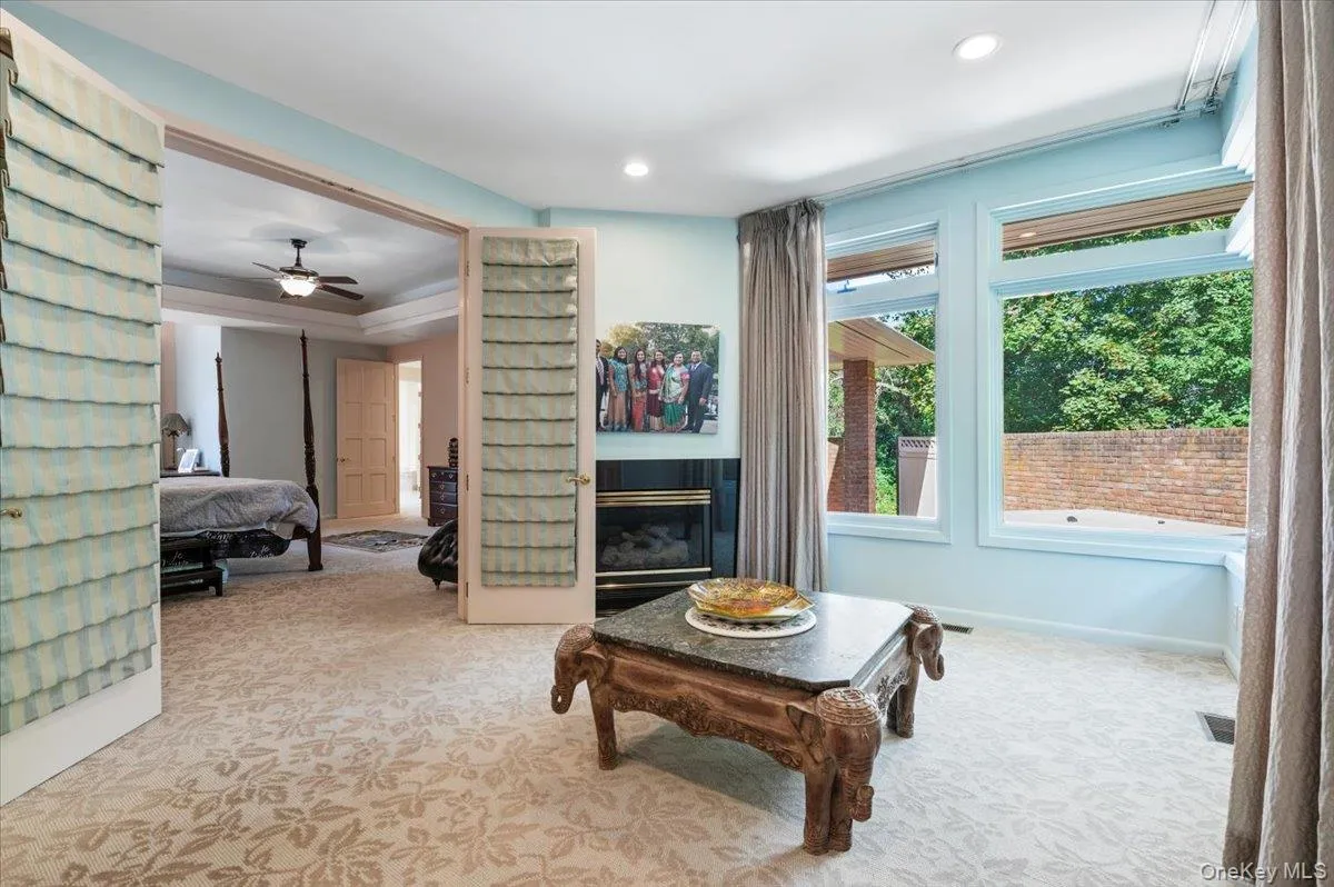 Living room with light colored carpet, a glass covered fireplace, a ceiling fan, and recessed lighting Living room with light colored carpet, a glass covered fireplace, a ceiling fan, and recessed lighting